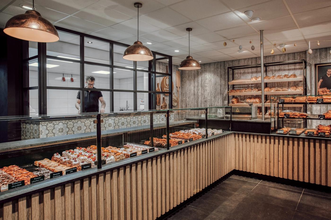 Toonbank met gebak en brood bij De Zeeuwse Bakclub, met houten fronten en hanglampen.