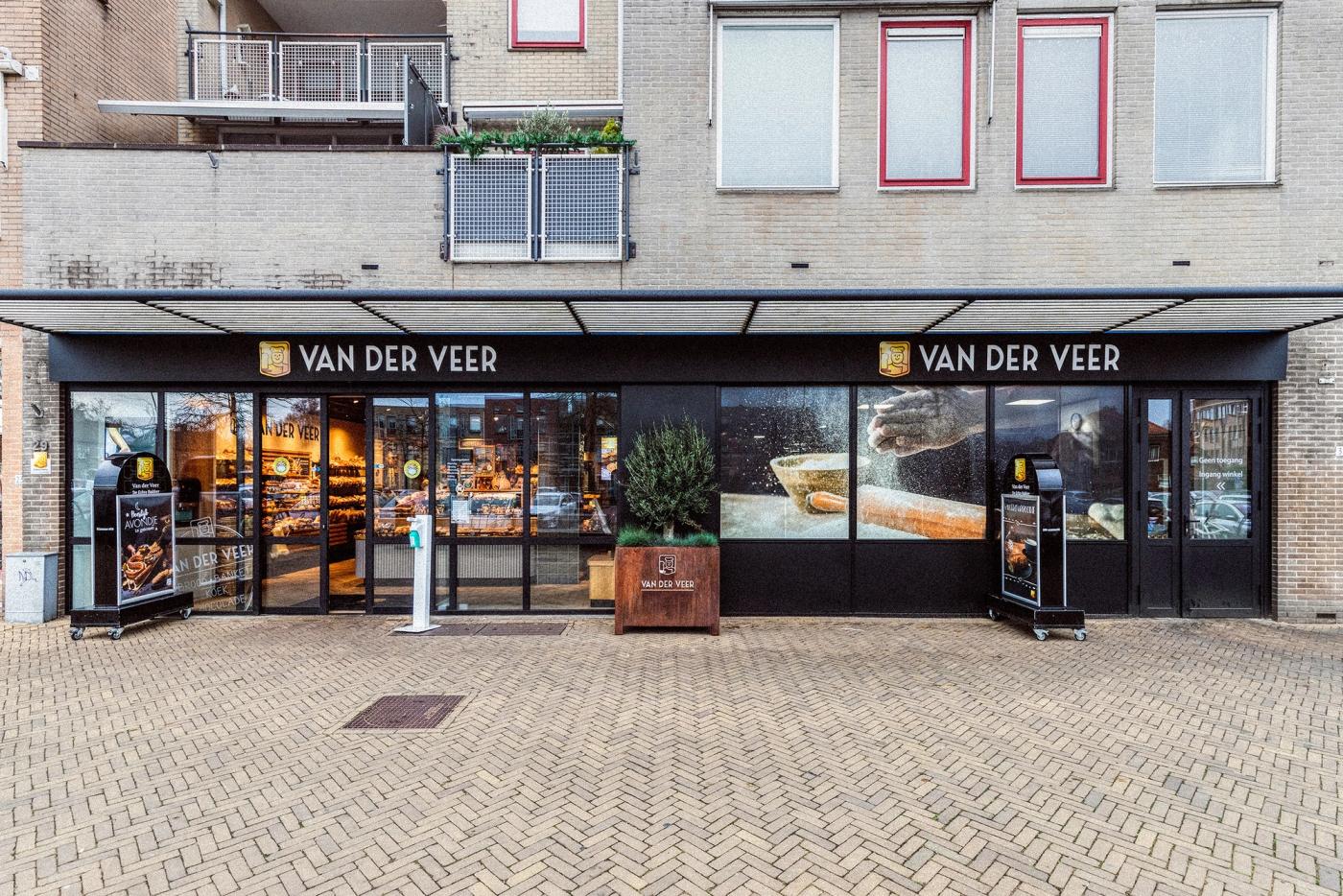 Gevel van Bakker Van der Veer in Barneveld, met twee etalages en het logo boven de entree.