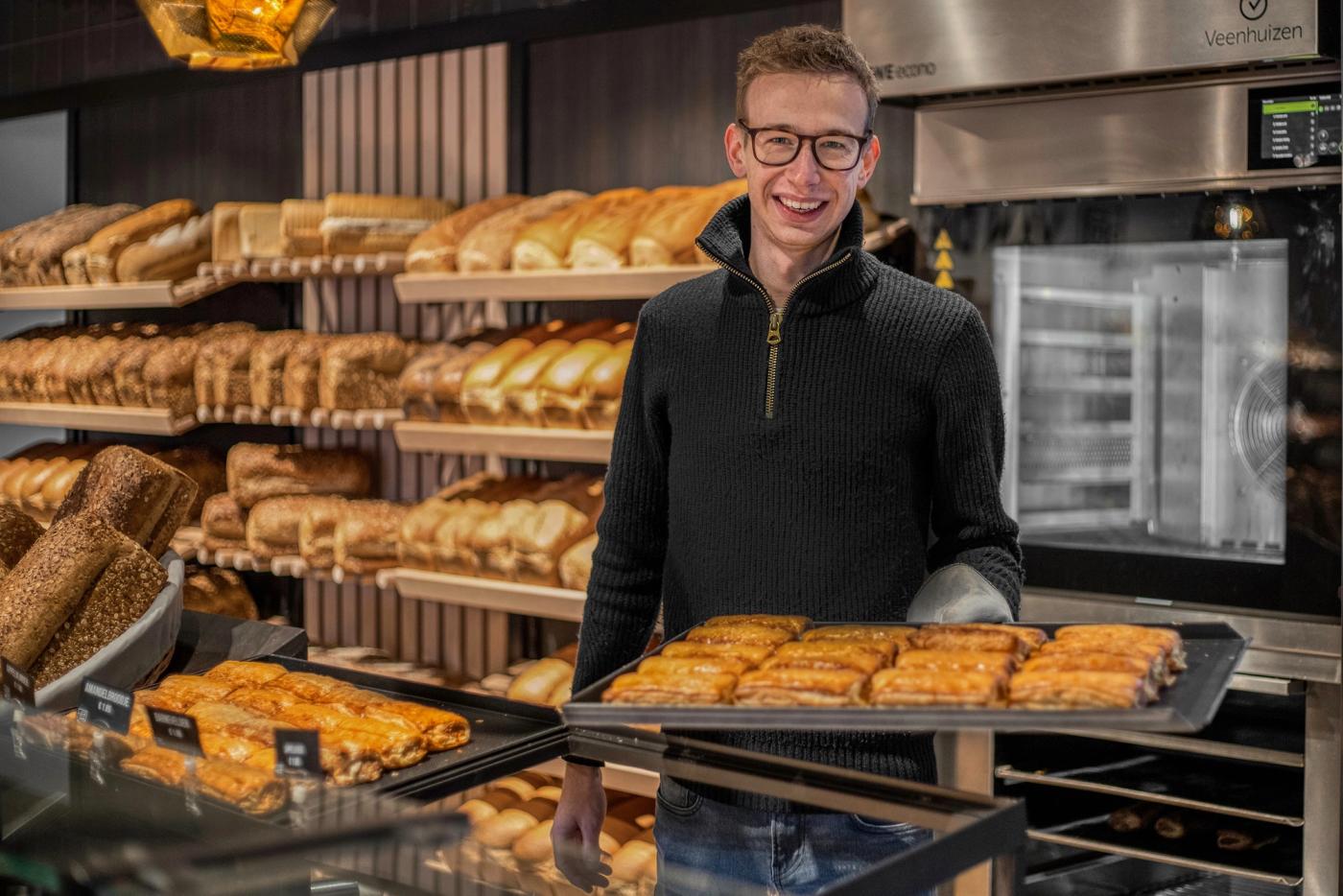 Bakker met een bakplaat vers gebak voor de broodwand bij Bakker Van der Veer in Barneveld.