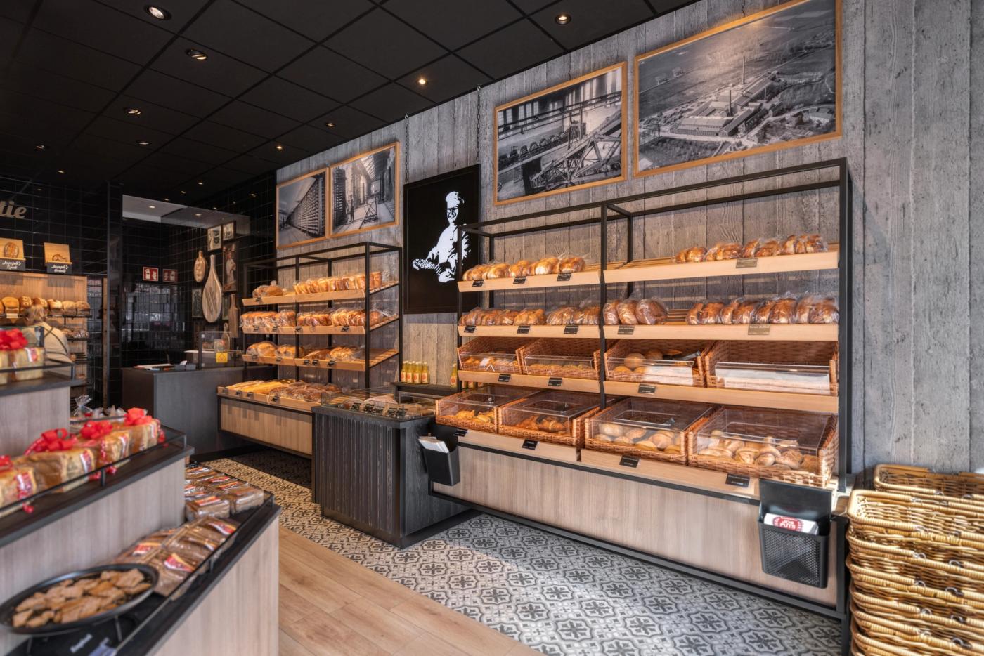 Ambachtelijke broodpresentatie bij Bakkerij Jos Puts in Echt, met warme houtaccenten, industriële details, historische fotografie en maatwerk winkelmeubilair ontworpen door Infrashop.