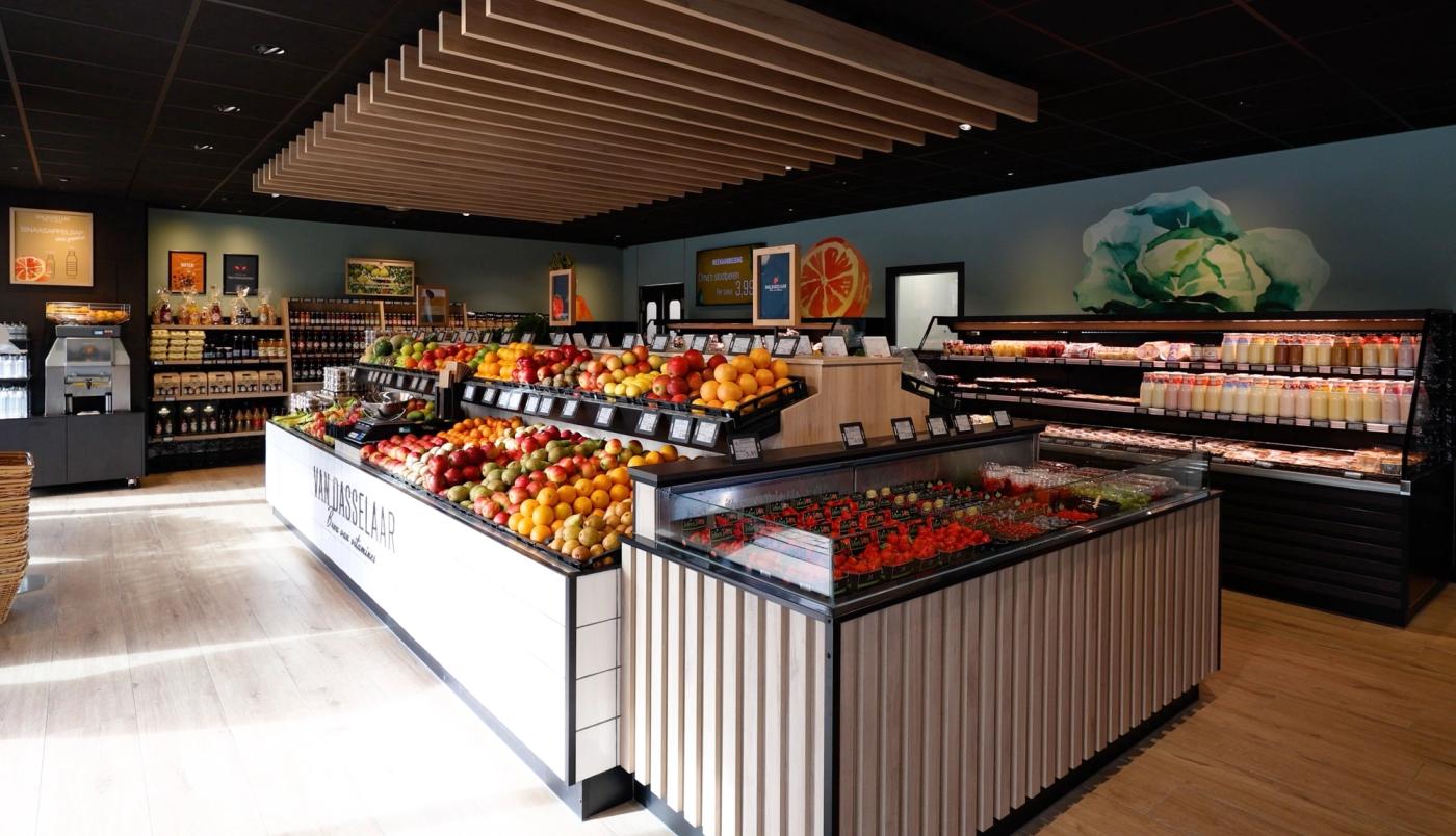 Ruim winkelinterieur van Van Dasselaar Groenten in Voorthuizen met kleurrijke fruitpresentatie, gekoelde versproducten, houten lattenplafond en natuurlijke materialen die de versbeleving versterken.