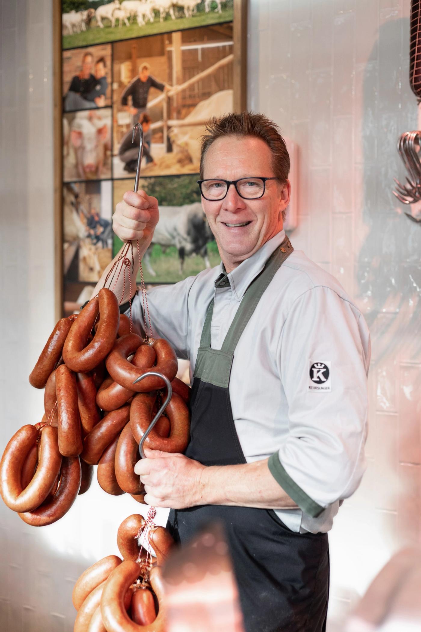 Slager met een bundel rookworsten bij Keurslagerij Hans Halman in Den Helder.