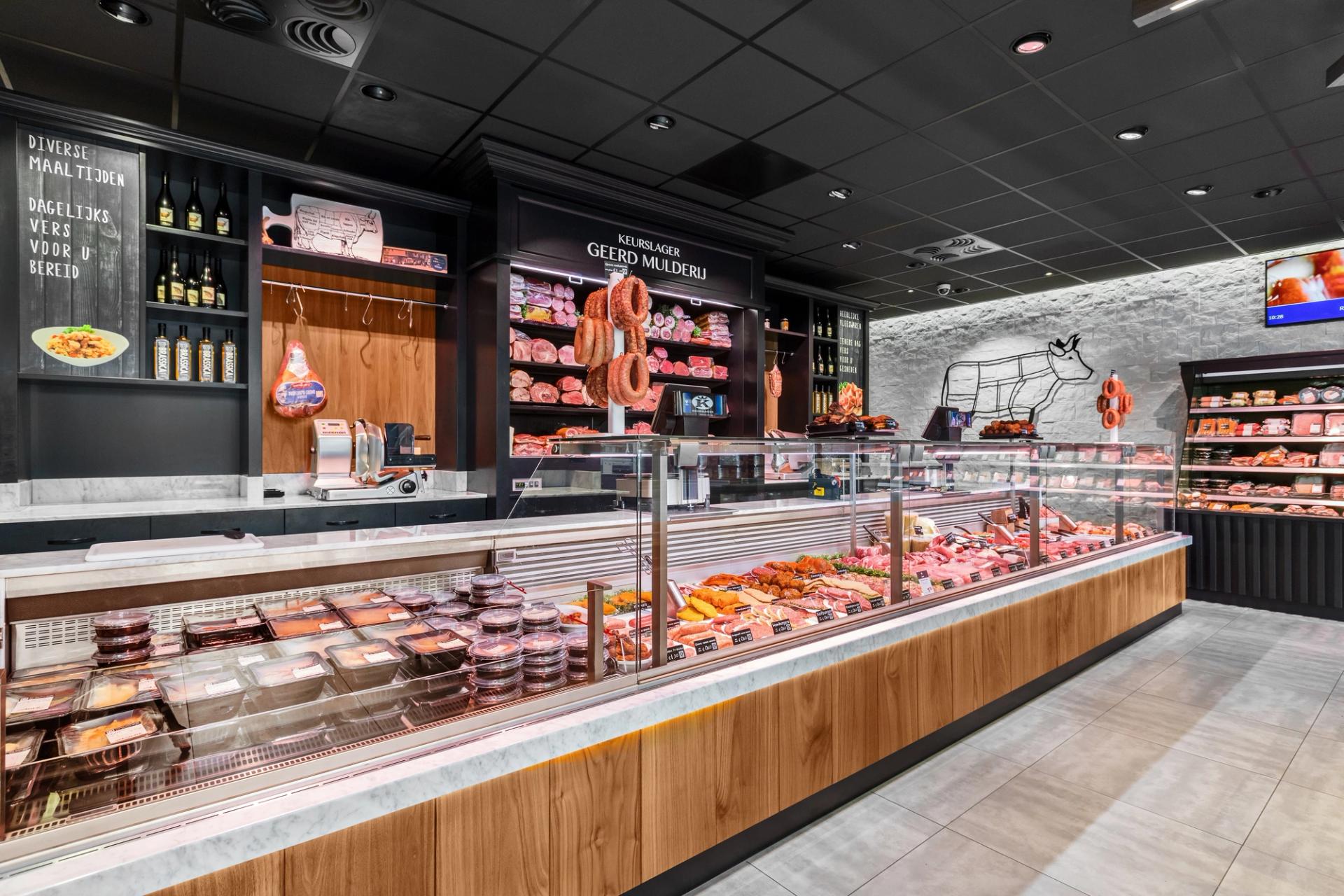 Winkelinterieur van Keurslagerij Geerd Mulderij in Voorthuizen, met een lange vleestoonbank met houten front en donkere wandkasten.