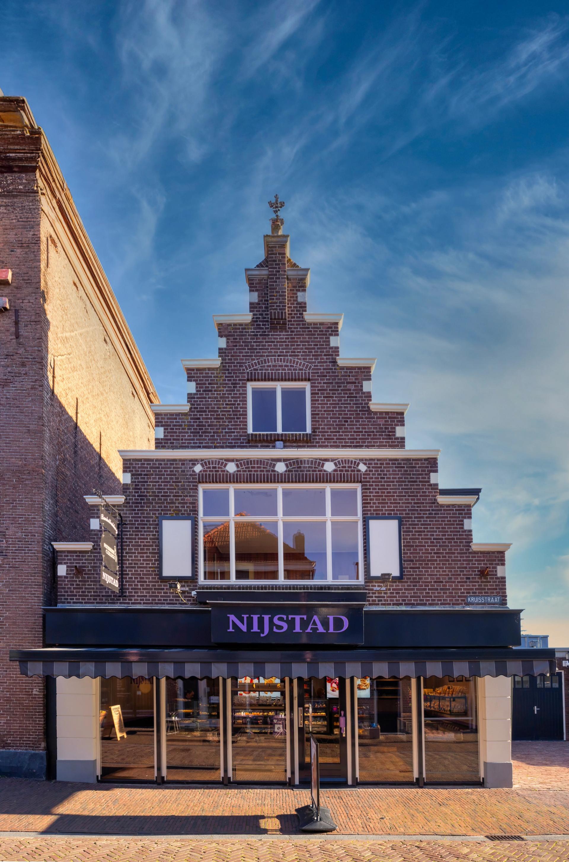 “Historische gevel van Banketbakkerij Nijstad met karakteristieke trapgevel en moderne winkelpui, waar het vernieuwde winkelinterieur zichtbaar is.”