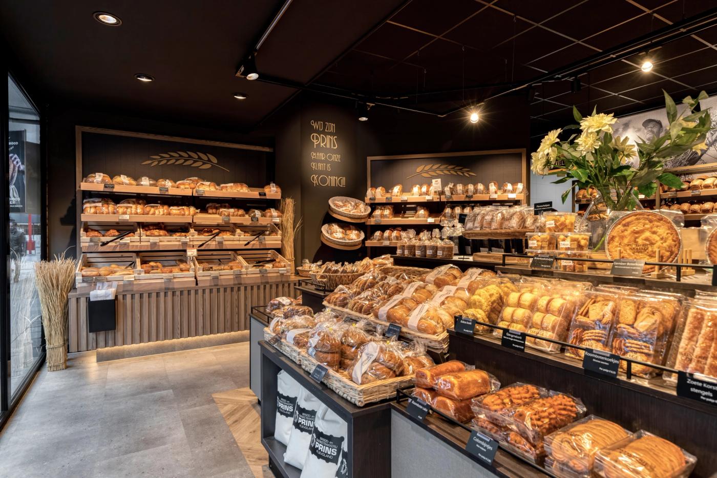 “Modern winkelinterieur van Brood- en Banketbakkerij Prins in Flevoland met ambachtelijke broodpresentatie, warme houtaccenten en sfeervolle verlichting.”