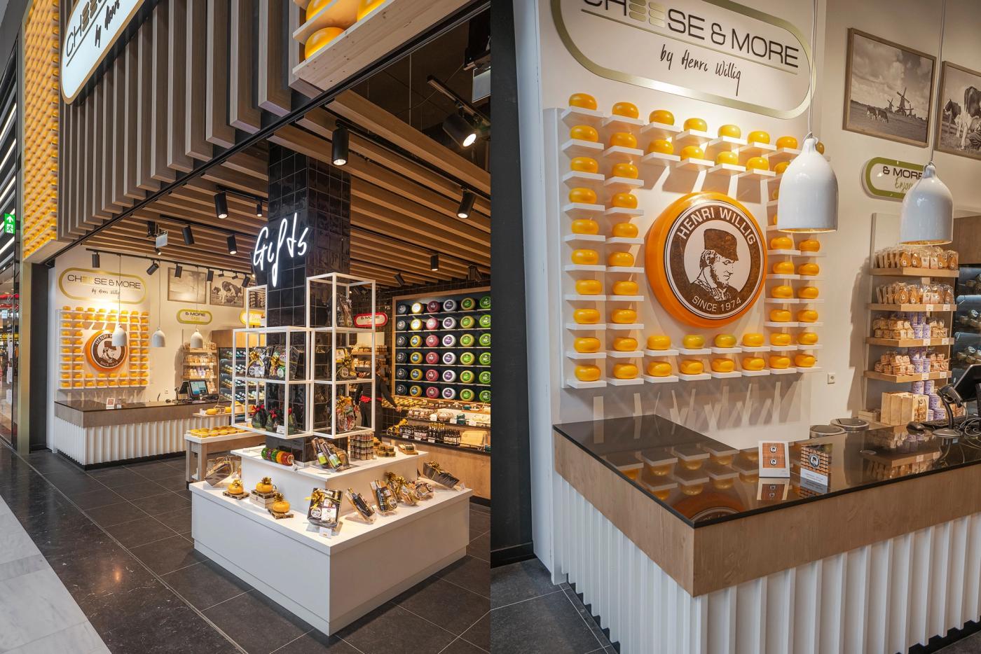 Doorkijk naar de entree van Cheese & More, met een kaaswand met een rond logo en een witte presentatietoonbank.