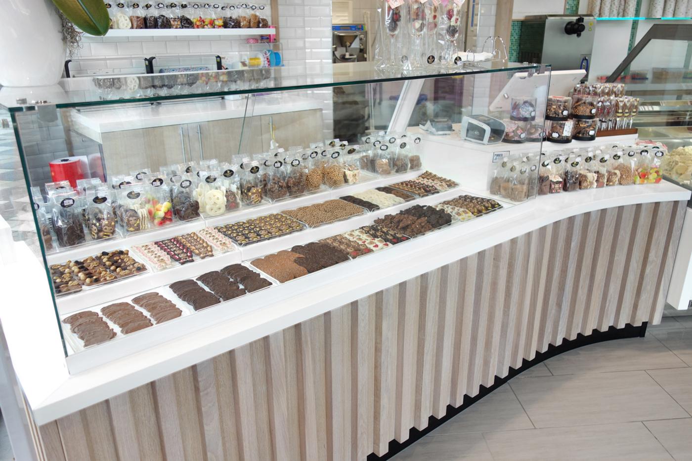 Maatwerk winkelinterieur voor chocolaterie en patisserie, ontworpen en gebouwd door Infrashop, met luxe chocoladepresentatie, bonbonvitrine en lichte houten toonbank.