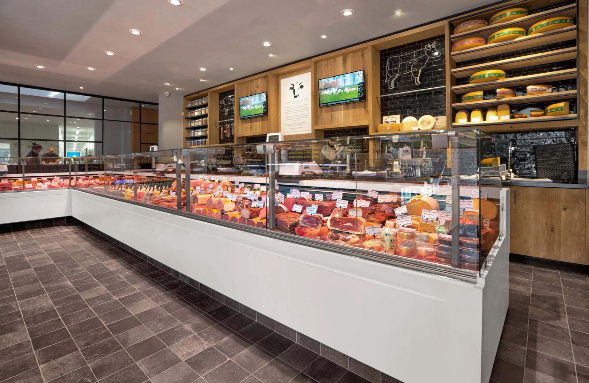 Lange witte vleestoonbank bij Slagerij Verstappen, met daarachter houten wandkasten met kaas en producten.