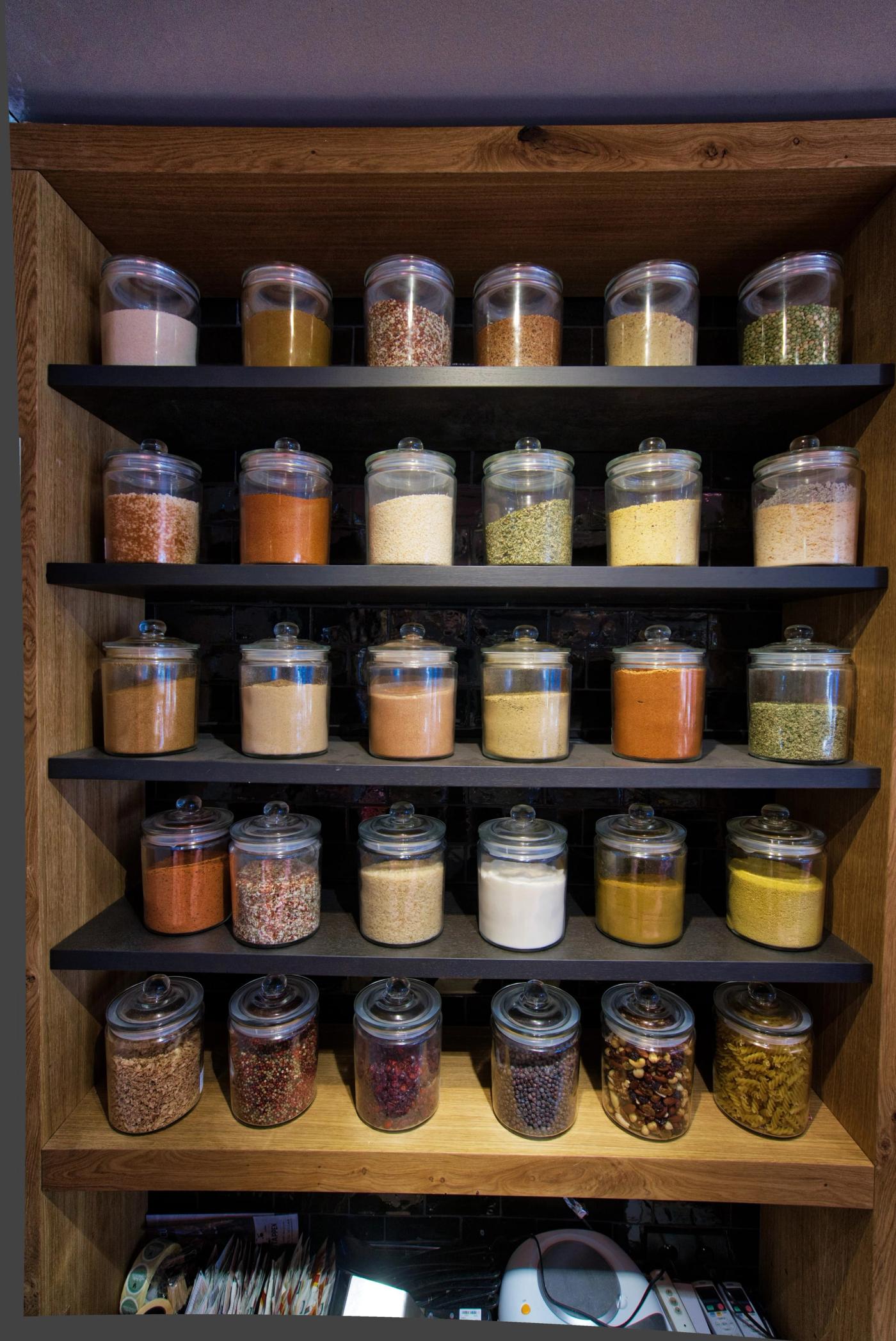 Wandkast met glazen potten kruiden en specerijen bij Slagerij Verstappen.