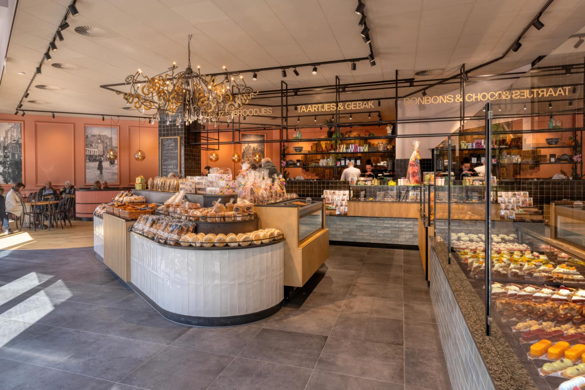 “Warm en eigentijds winkelinterieur van Patisserie Kwekkeboom in Amsterdam met luxe gebaksvitrines, ronde productpresentaties, industriële details en sfeervolle lunchroom, ontworpen en gebouwd door Infrashop.”