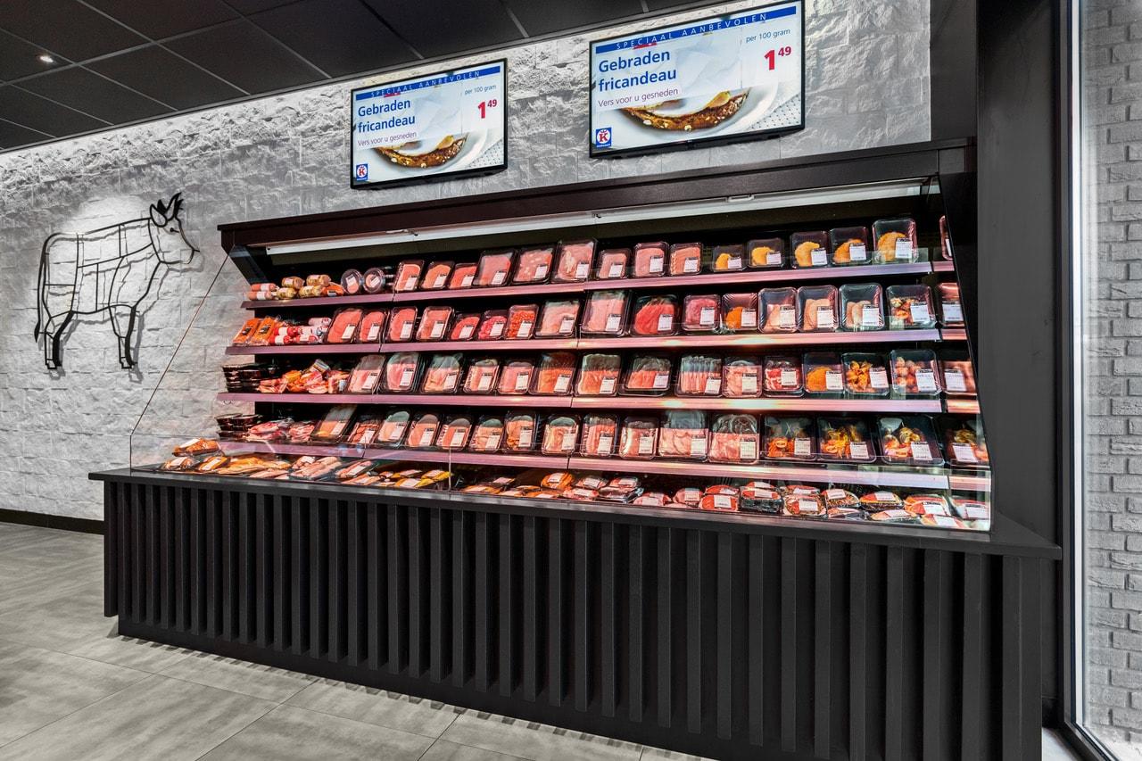 Koelwand met voorverpakt vlees en een wandtekening van een koe bij Keurslagerij Geerd Mulderij.