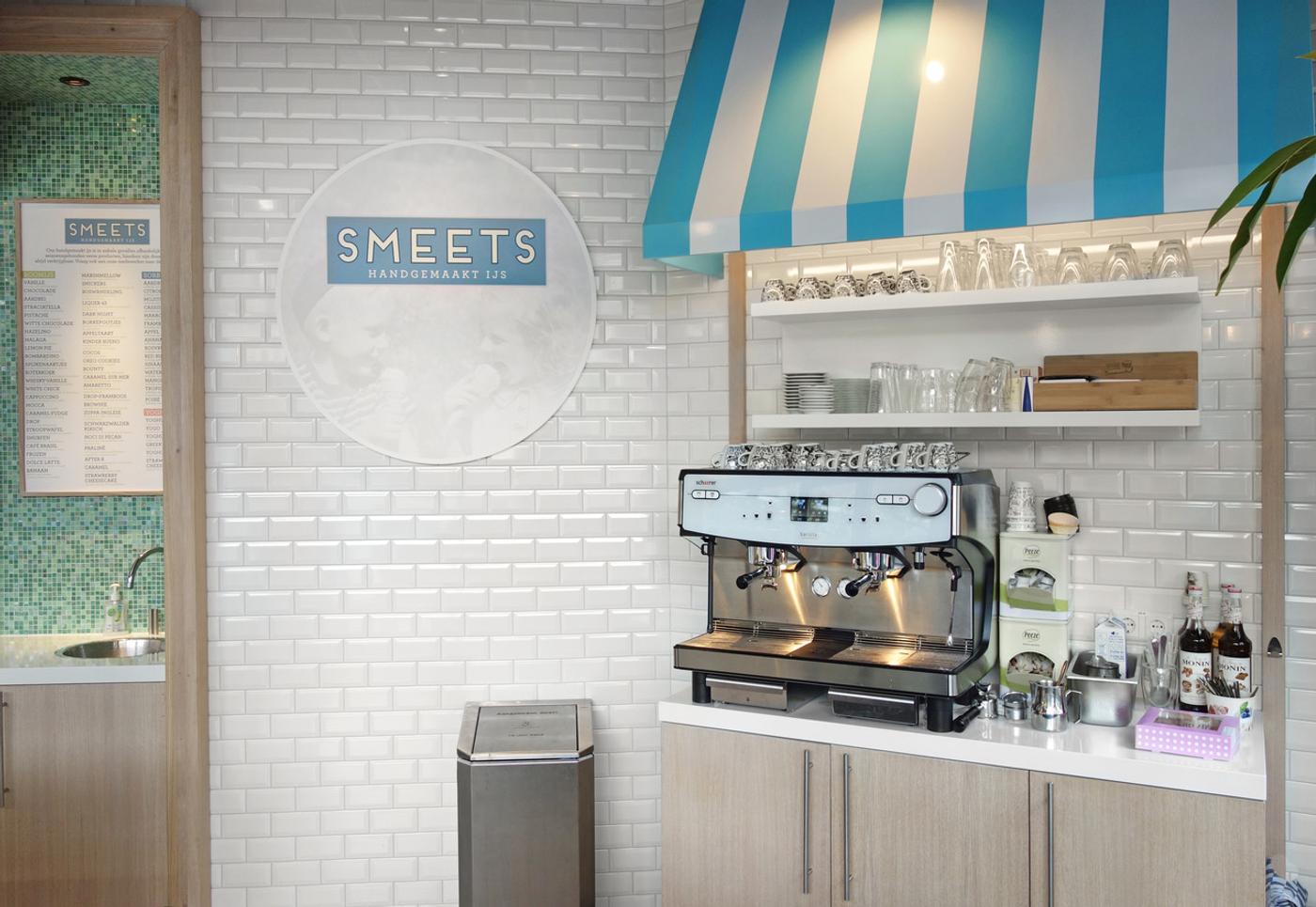 Modern ijssalon-interieur van Smeets, ontworpen en gebouwd door Infrashop, met maatwerk koffiehoek, lichte houtafwerking, witte metrotegels en karakteristieke blauw-witte luifel.