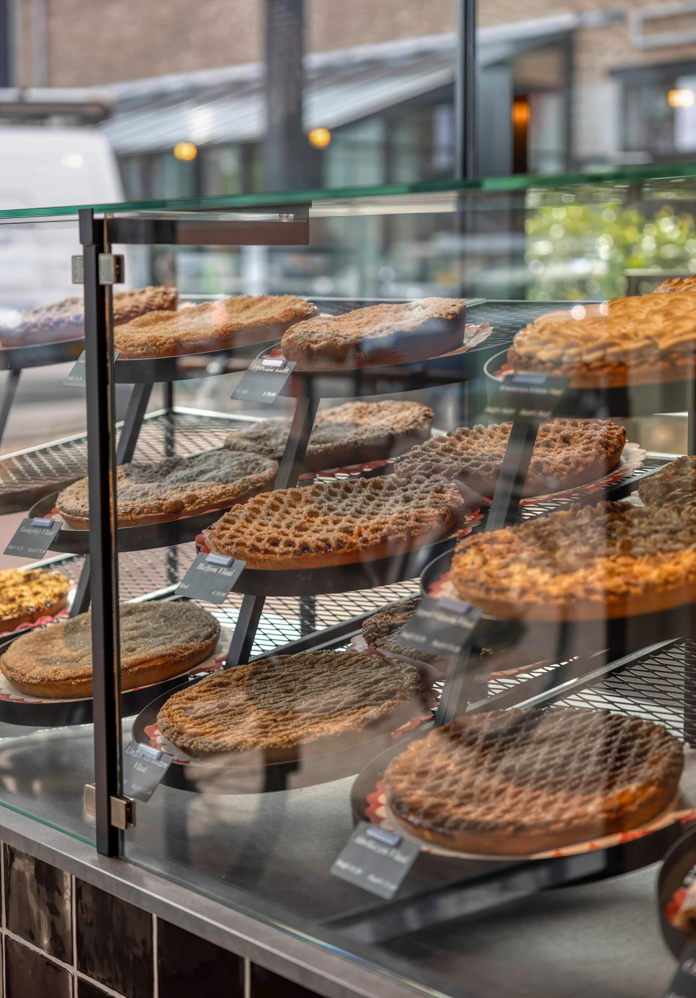 Royale vlaaienpresentatie bij Bakkerij Jos Puts in Echt, met verschillende ambachtelijke Limburgse vlaaien overzichtelijk en verleidelijk gepresenteerd in een glazen vitrine.
