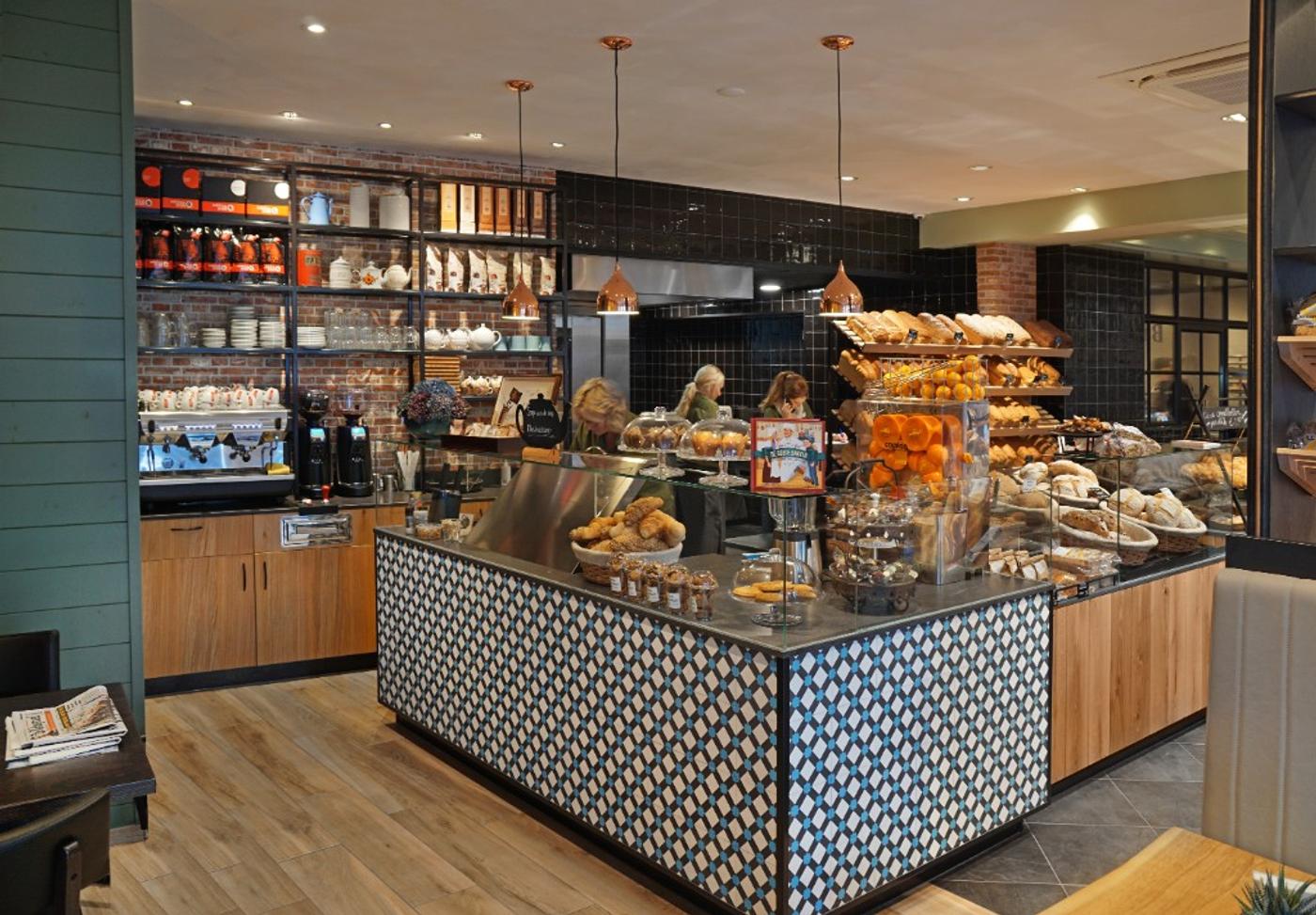 Modern bakkerij-interieur ontworpen en gebouwd door Infrashop, met maatwerk toonbank, houten broodpresentatie, koffiehoek en warme industriële details.