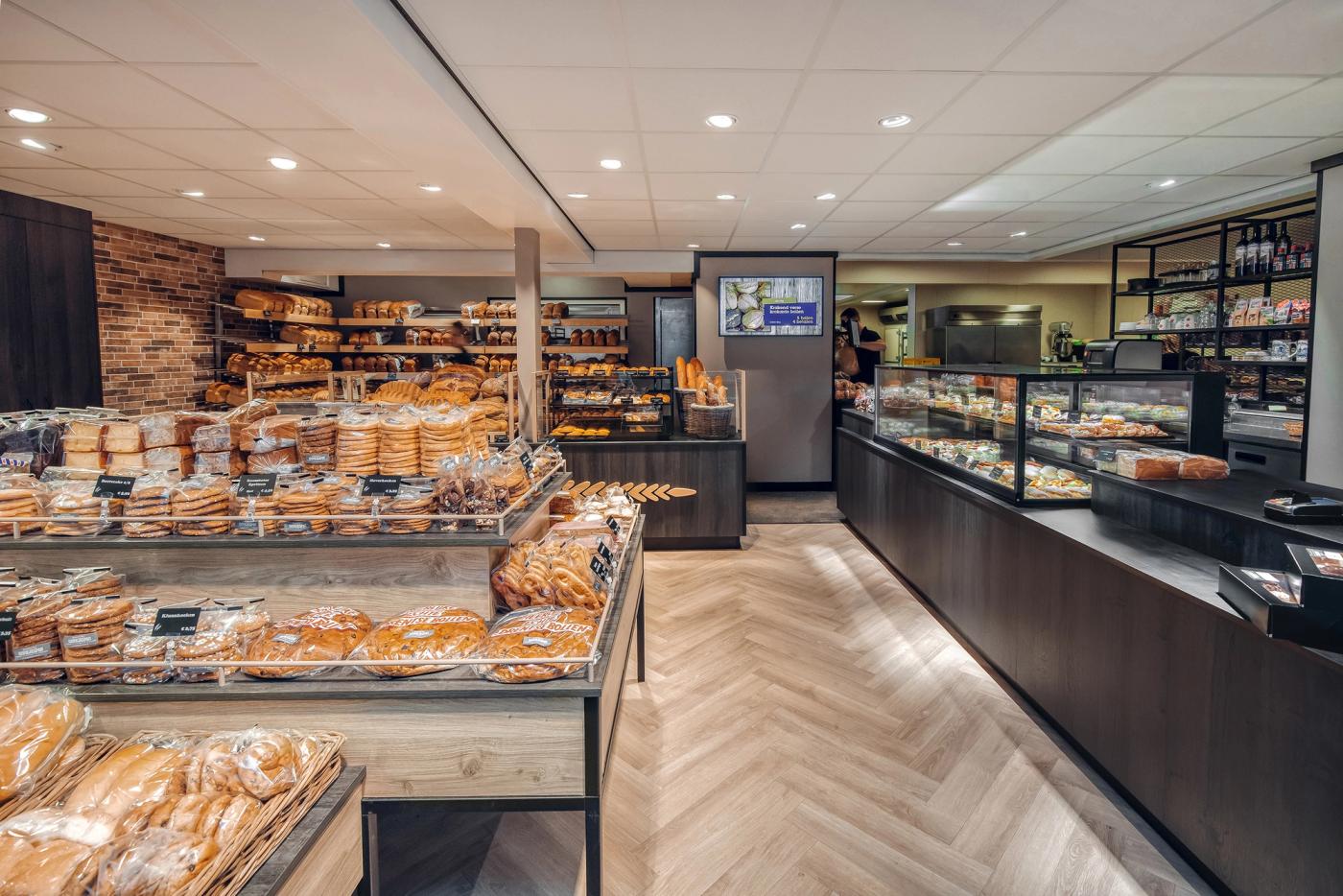 Ruim winkelinterieur van Bakkerij Hamersma in Grootegast, met uitgebreide brood- en banketpresentaties, warme houttinten en maatwerk winkelmeubilair ontworpen en gerealiseerd door Infrashop.