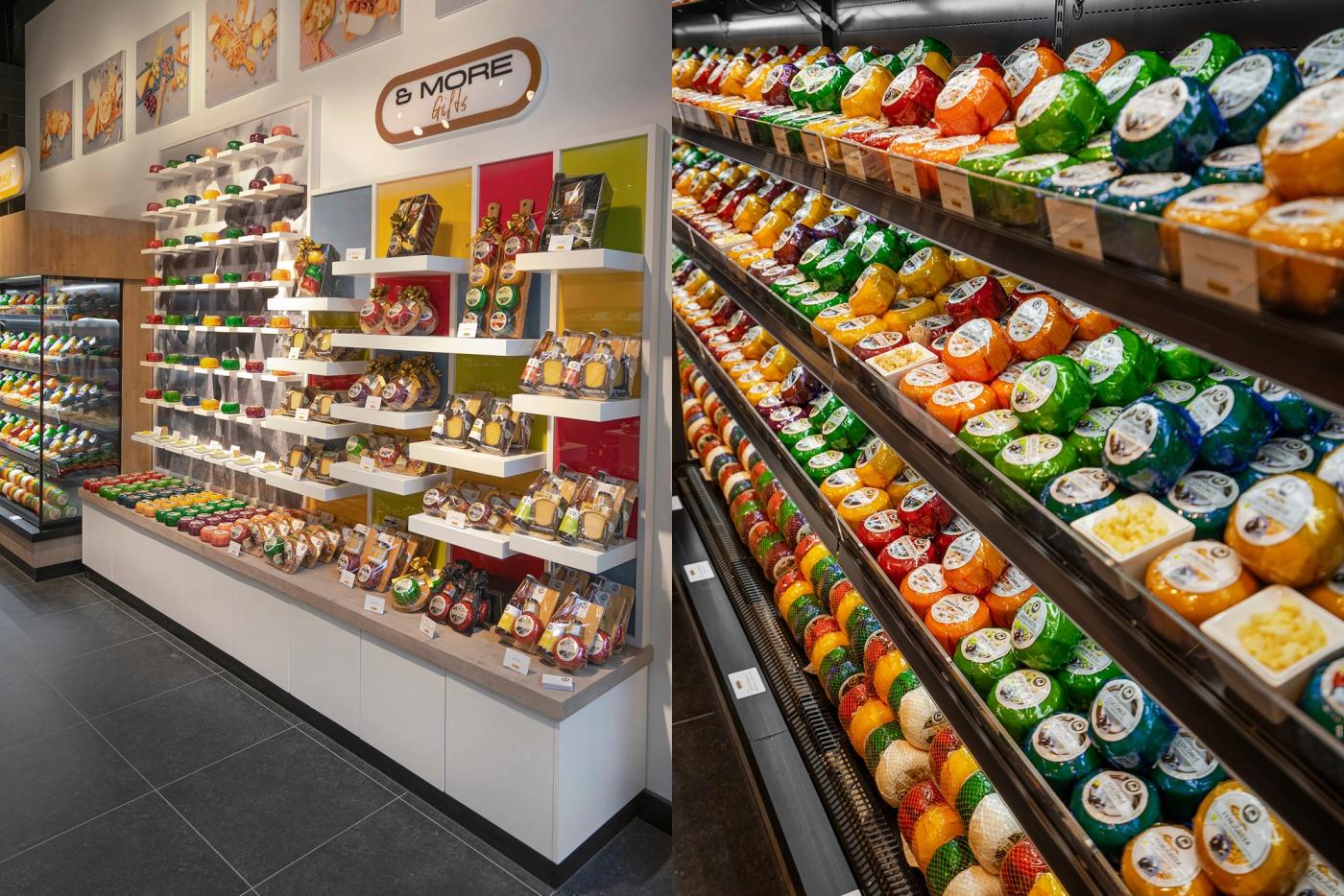 Koelwand met kleurrijk verpakte kazen naast een wandpresentatie met kaascadeaus bij Cheese & More.