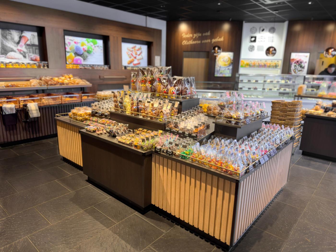 Modern winkelinterieur van Bakkerij Olsthoorn in Naarden, met centrale presentatie van chocolade en zoetwaren, warme houtaccenten en stijlvolle productvitrines.