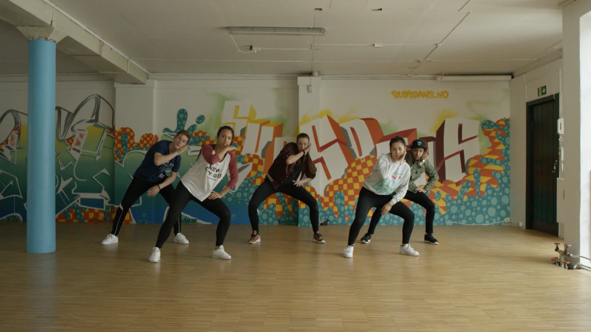 Dansere i en dansesal med grafitti på veggen
