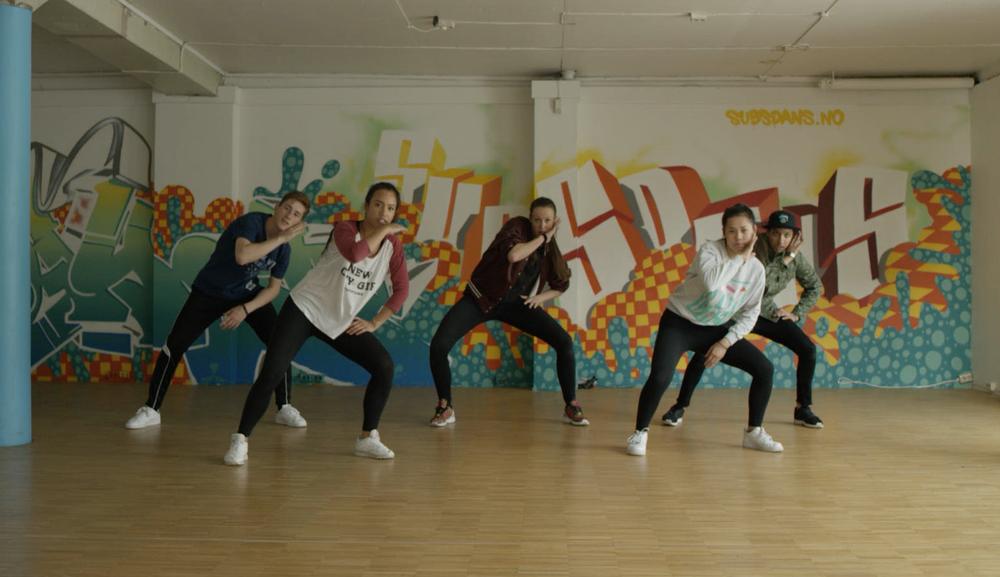 Dansere i en dansesal med grafitti på veggen