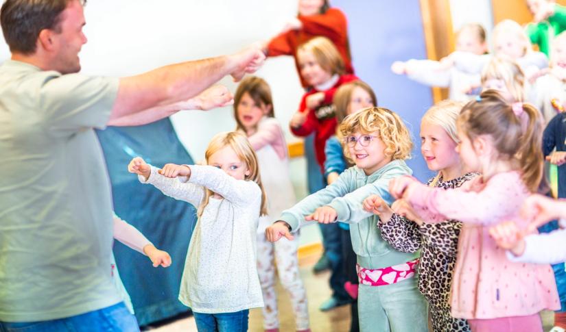 Barn som leker en sanglek ledet av en voksen