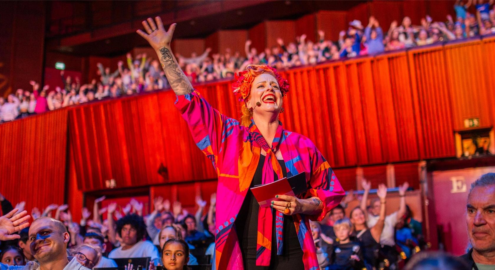 Programleder Silya hilser elever fra hele landet som ser på opptakene fra Skolenes sangdag 2025 i Oslo konserthus. I salen synger over 1000 elever sammen med Oslo-filharmonien.
