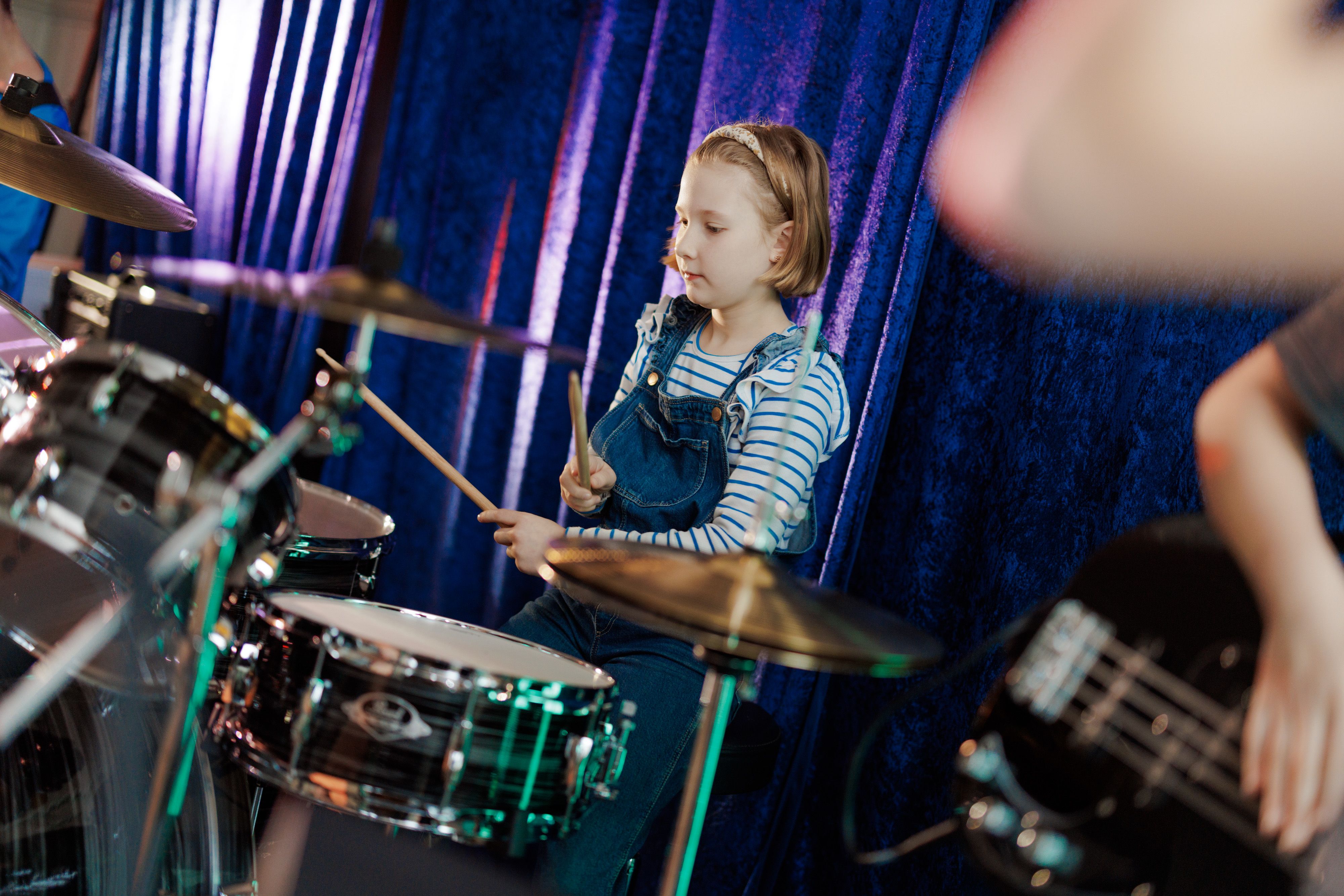 En jente spiller på trommesett på et musikkrom