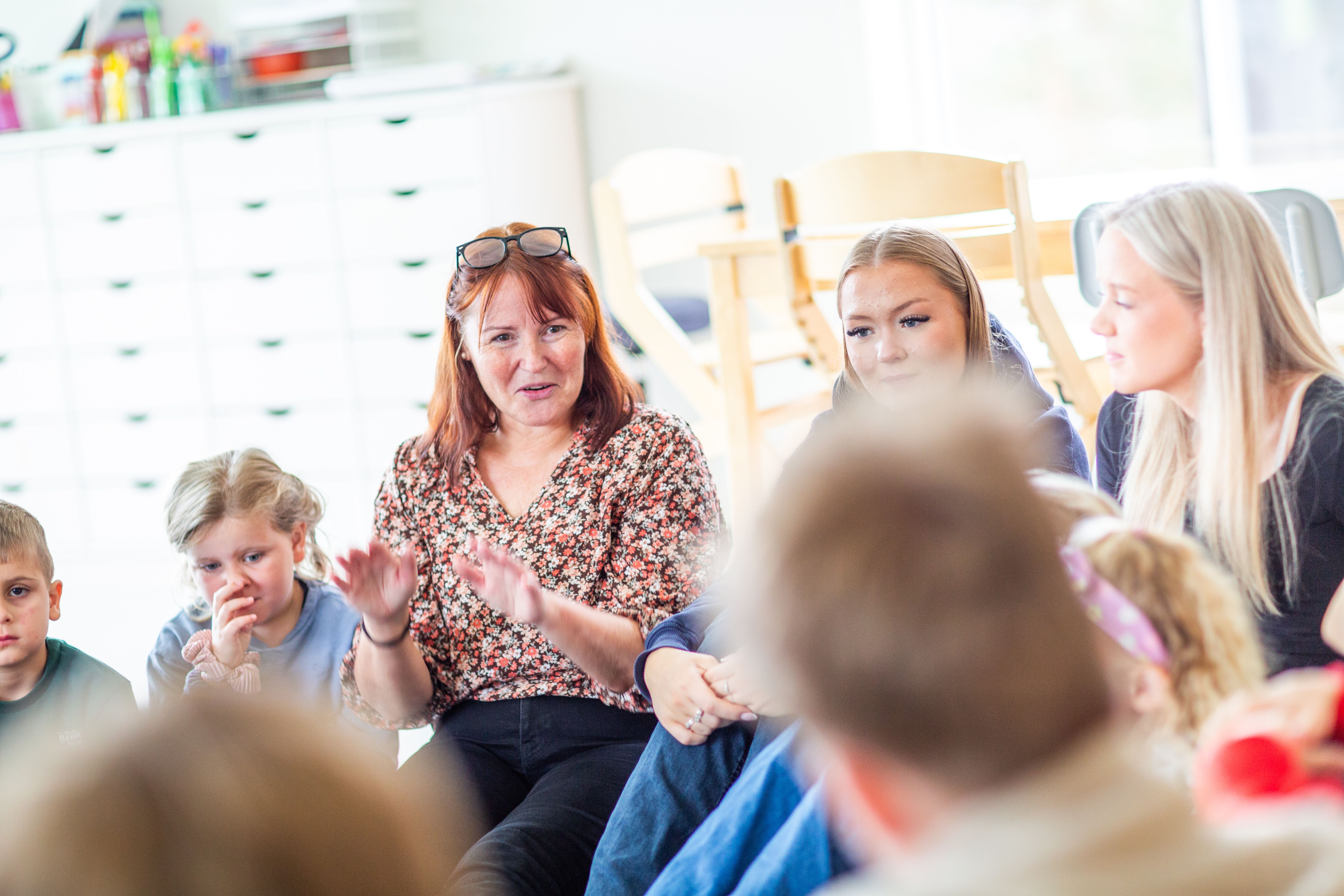 Ungdommer og barn synger sammen med en lærer
