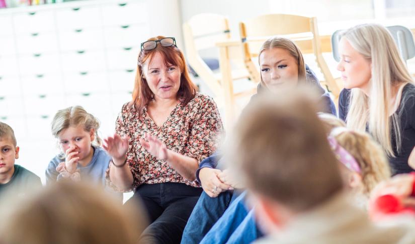 Ungdommer og barn synger sammen med en lærer