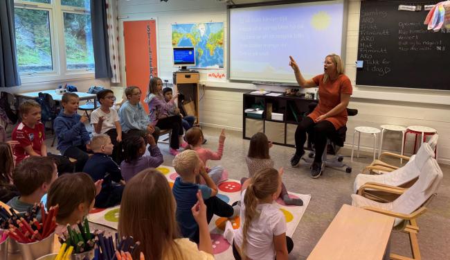 Elever og lærer synger sammen i klasserommet