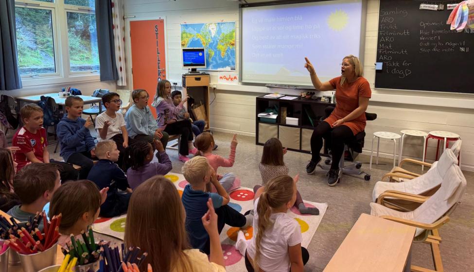 Elever og lærer synger sammen i klasserommet