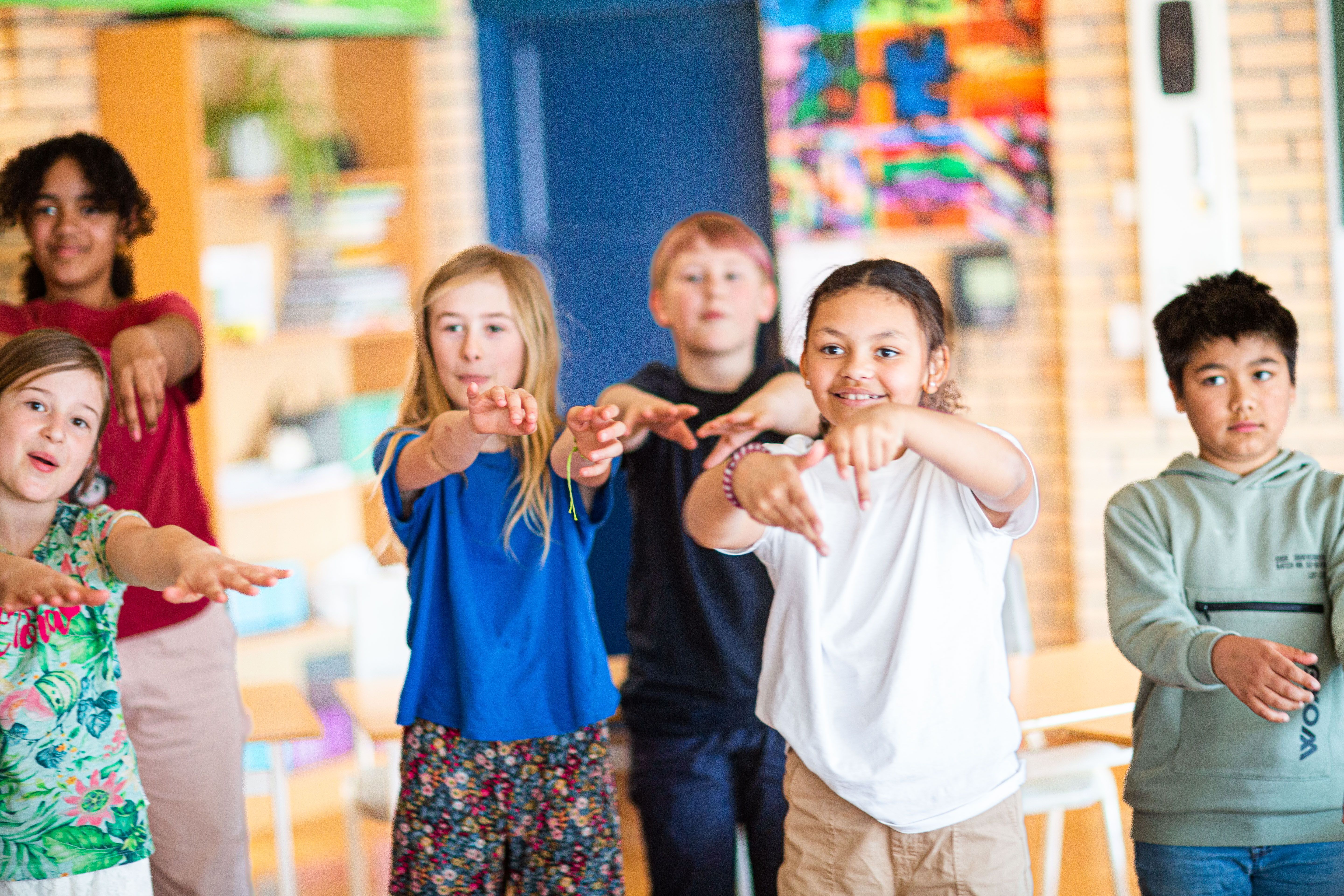 Elever synger og danser i klasserommet.