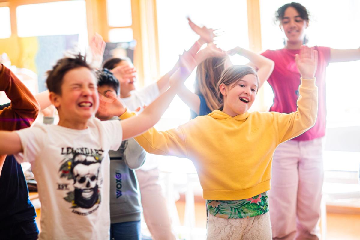 Elever danser og synger for full hals i klasserommet.