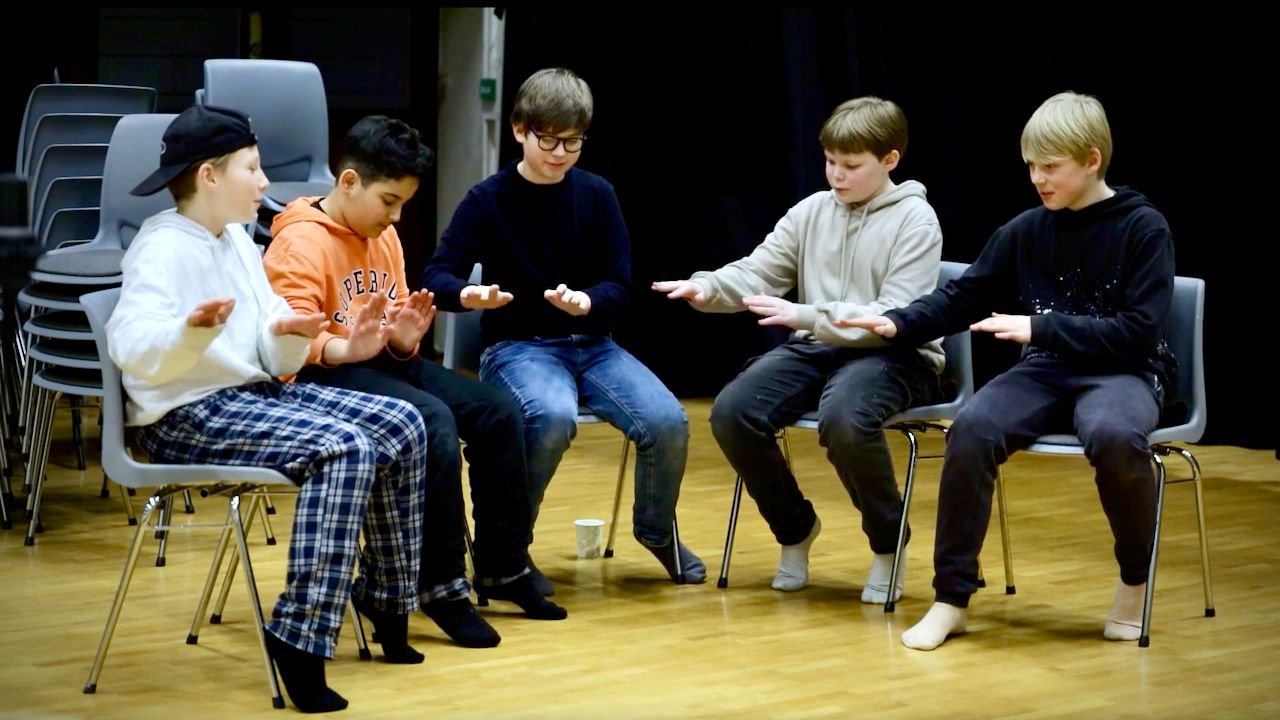 Fem elever synger og klapper