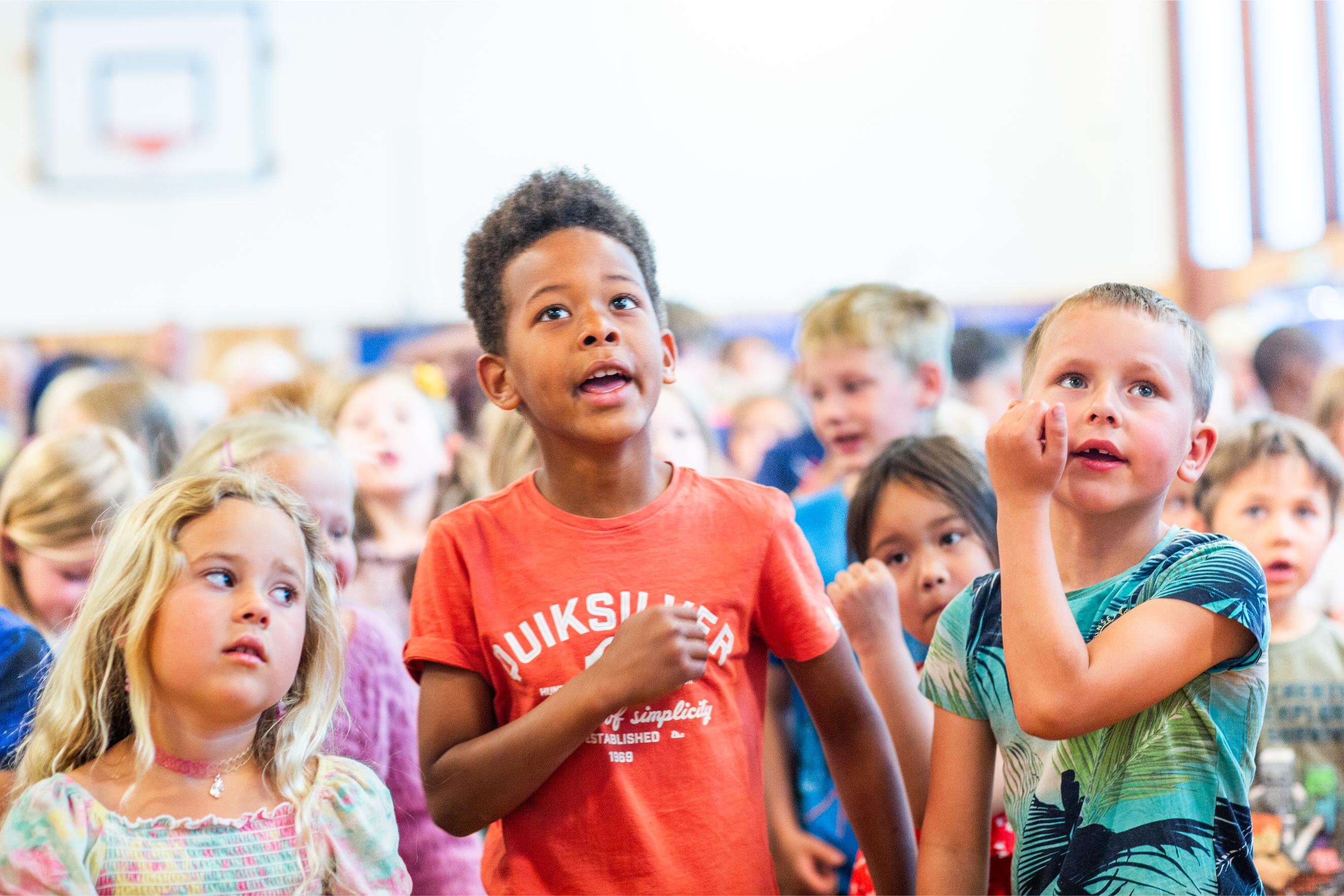 Elever synger sammen i gymsalen