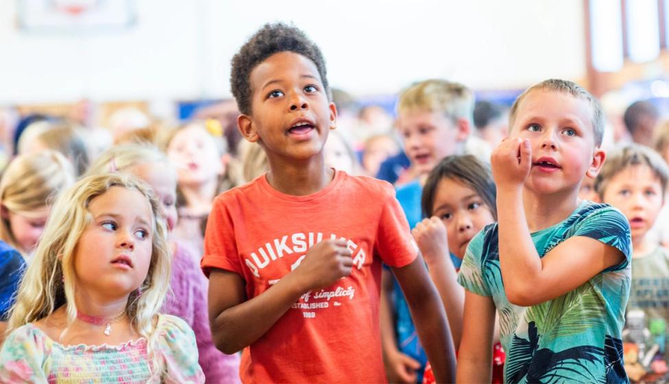 Elever synger sammen i gymsalen