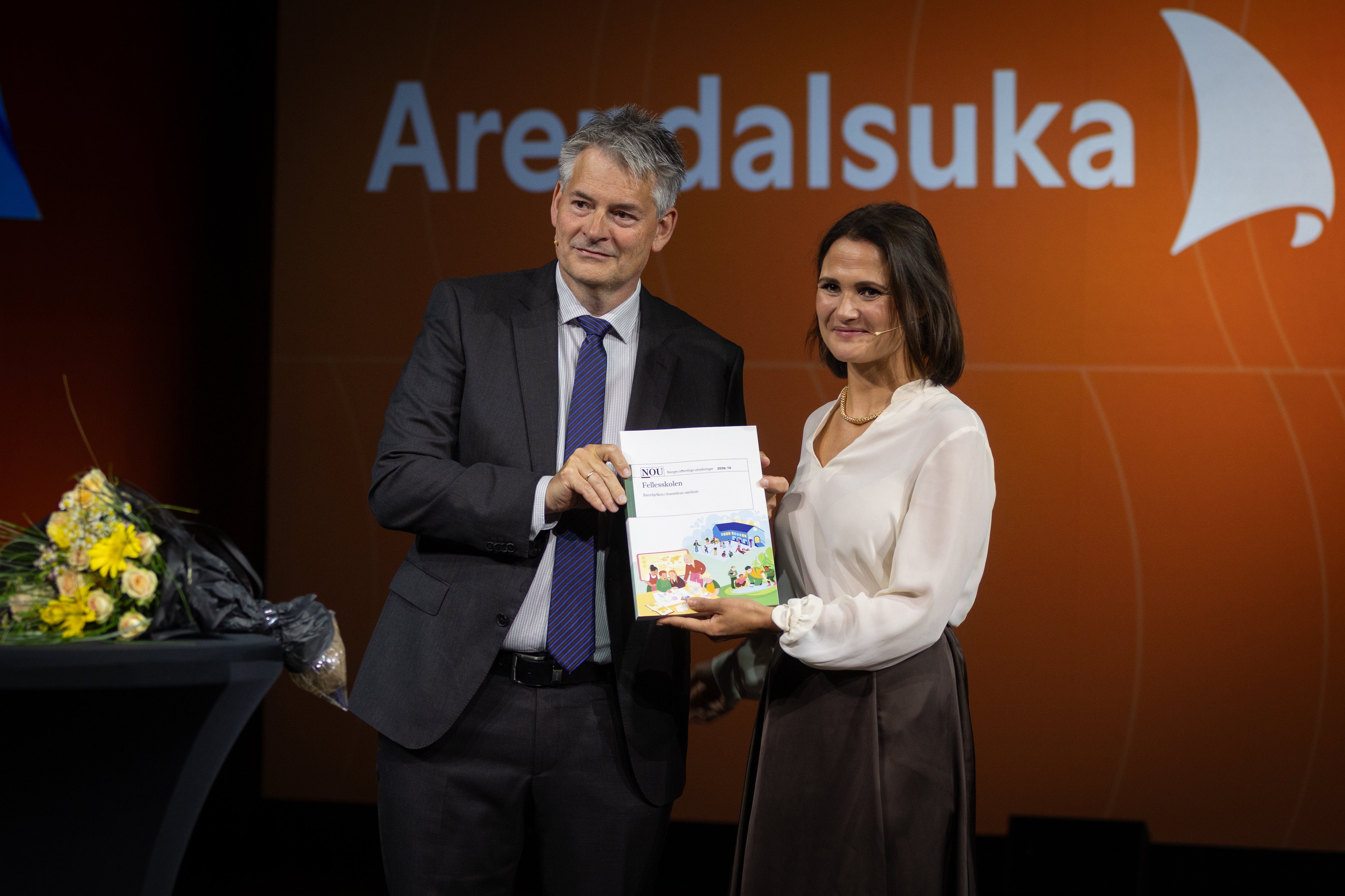 Utvalgets leder og kunnskapsministeren poserer for fotograf med et eksemplar av rapporten.