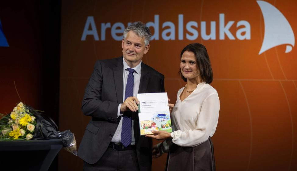 Utvalgets leder og kunnskapsministeren poserer for fotograf med et eksemplar av rapporten.