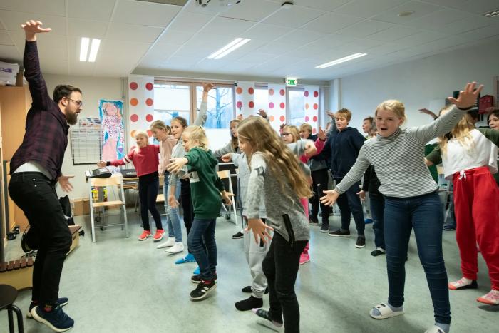 Elever danser i klasserommet.