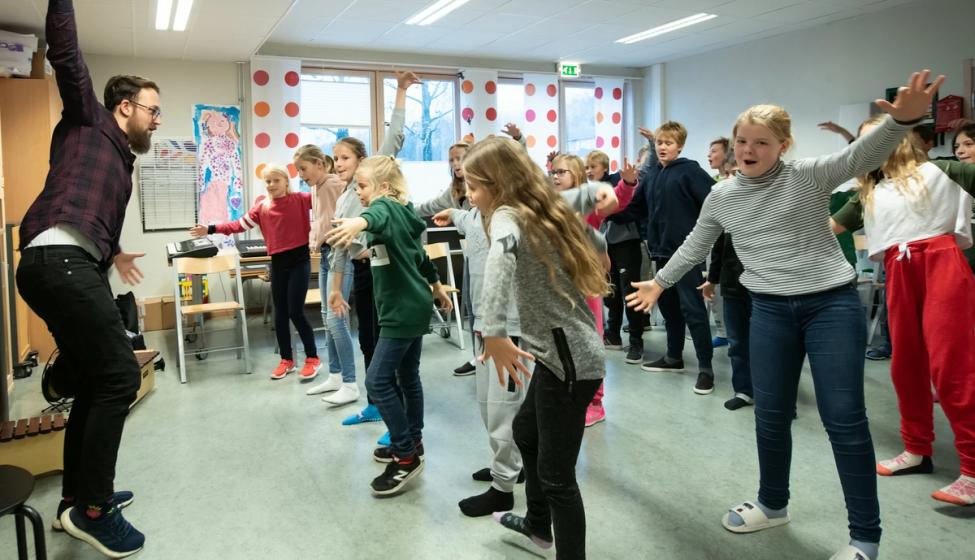 Elever danser i klasserommet.