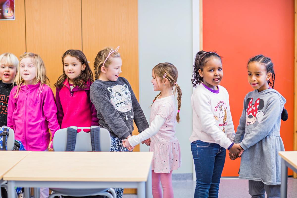 Elever synger og holder hverandre i hendene.