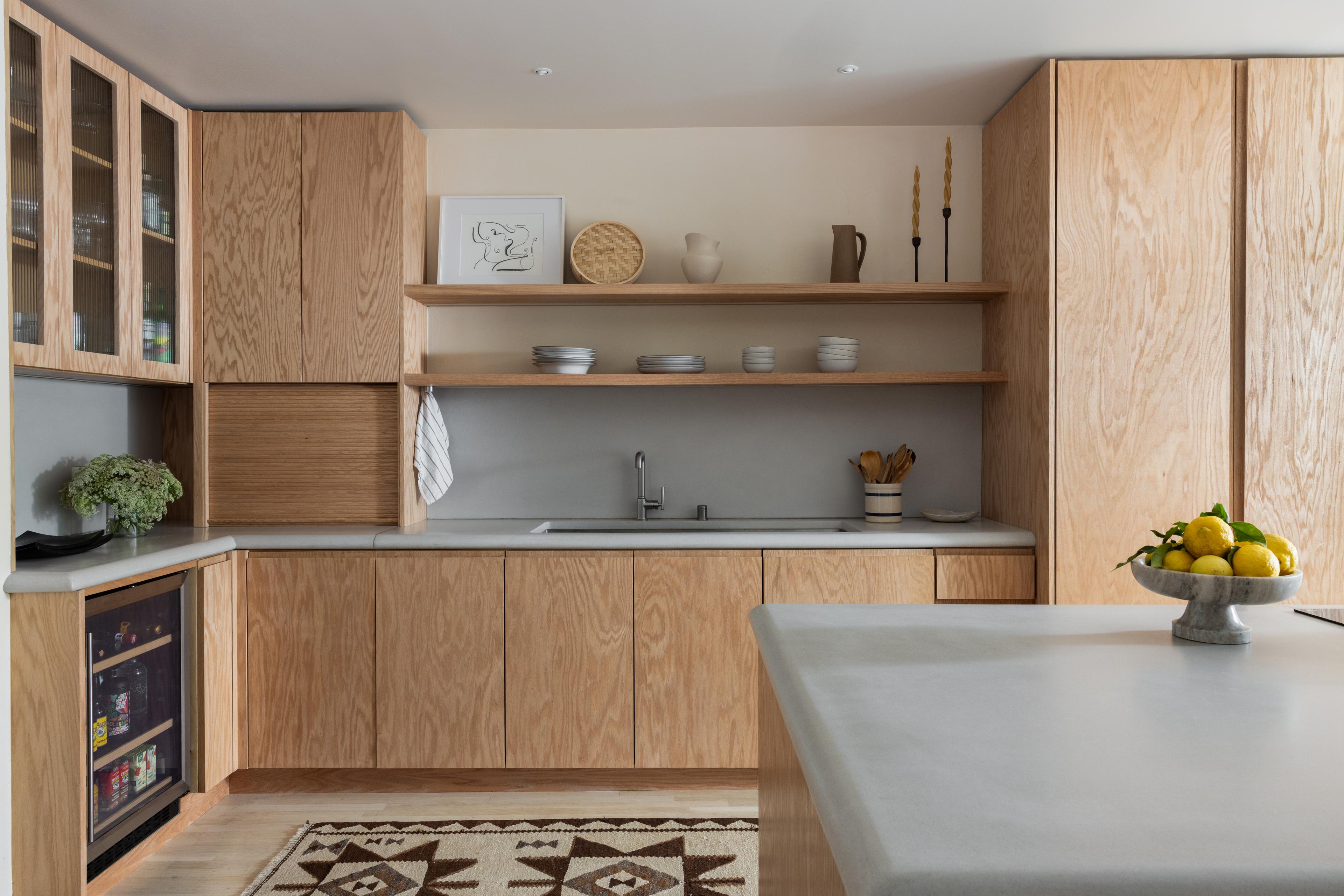 Kitchen with open red oak shelving, concrete backsplash, and styled ceramics designed by Studio VAE, San Francisco interior designer.