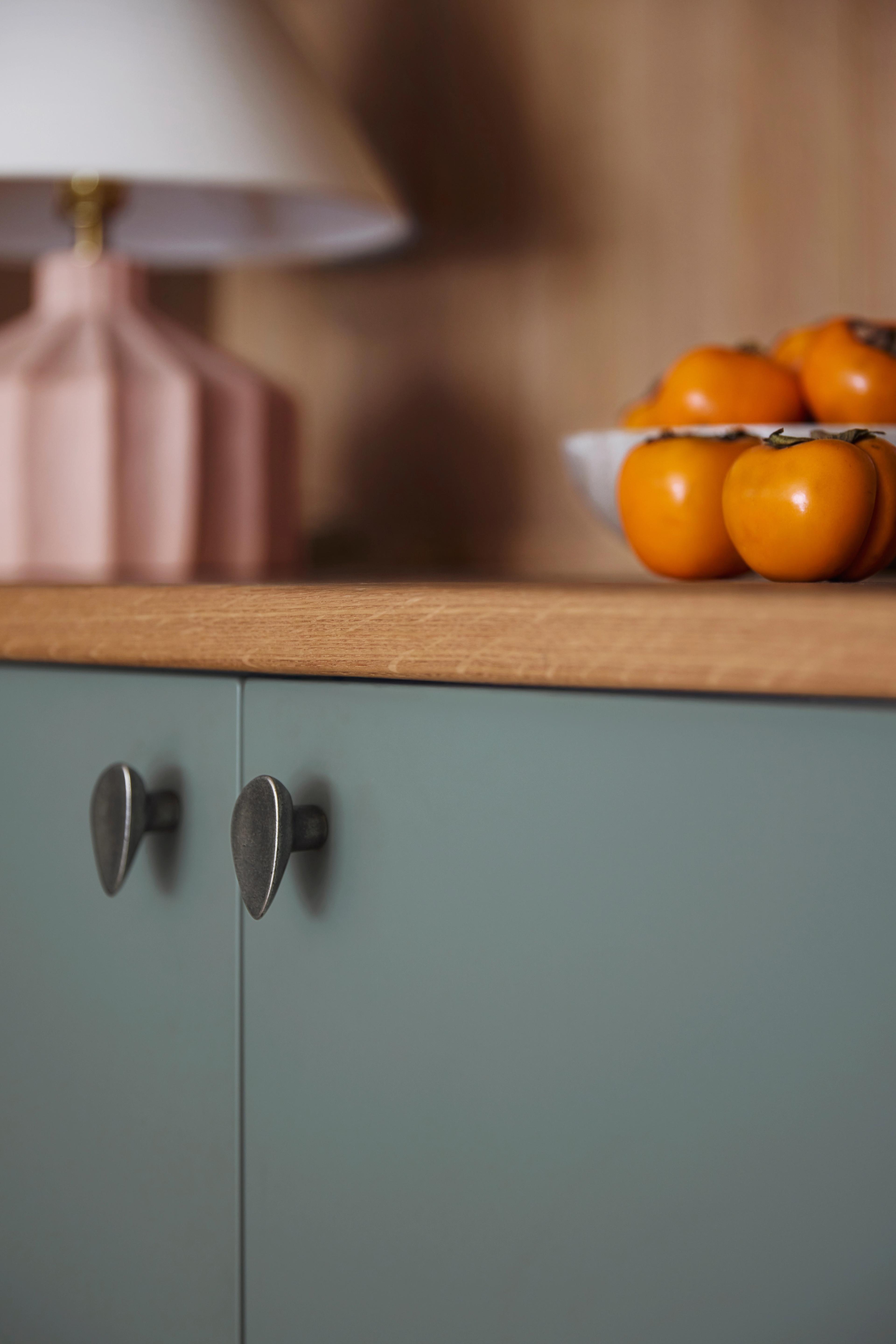 Kitchen detail with sage green cabinets, cast bronze knobs, and wood plank counter in Outer Sunset home designed by Studio VAE, San Francisco interior designer.