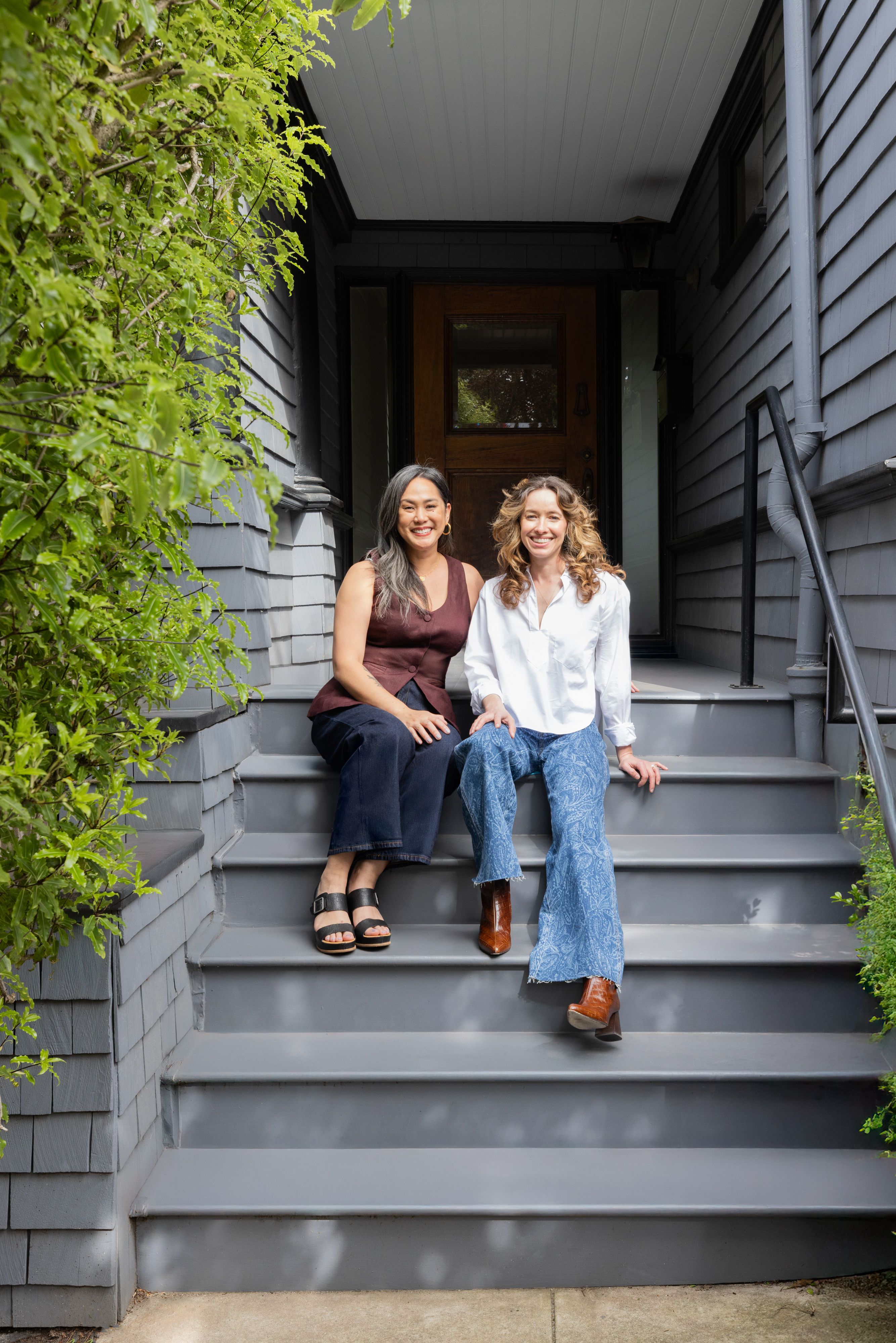 Veronica Jurist and Aggie Revane, principal designers and co-owners of Studio VAE, sitting on the front steps of a house