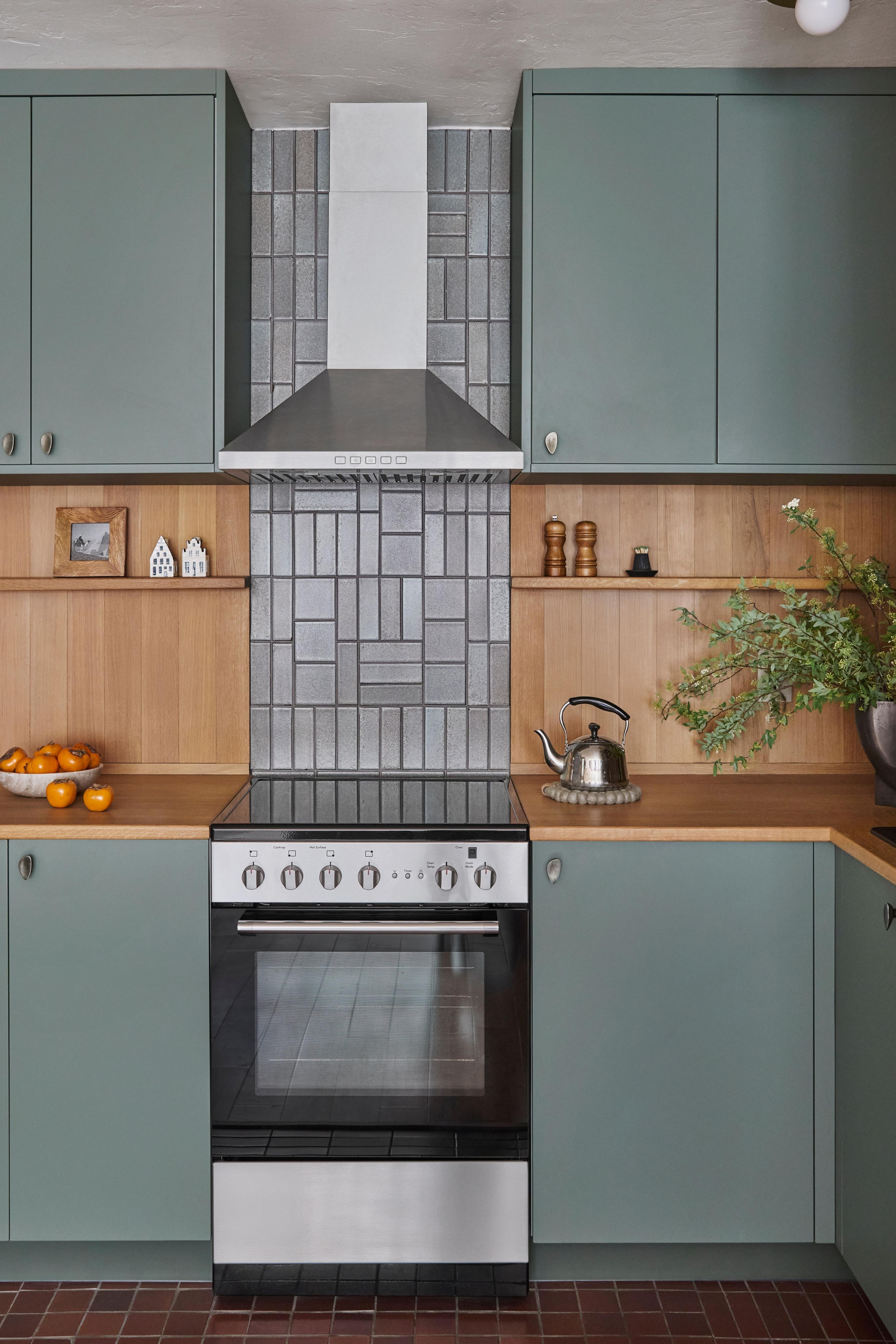 Kitchen with sage green cabinets, white oak surround, and patterned tile backsplash, designed by Studio VAE.