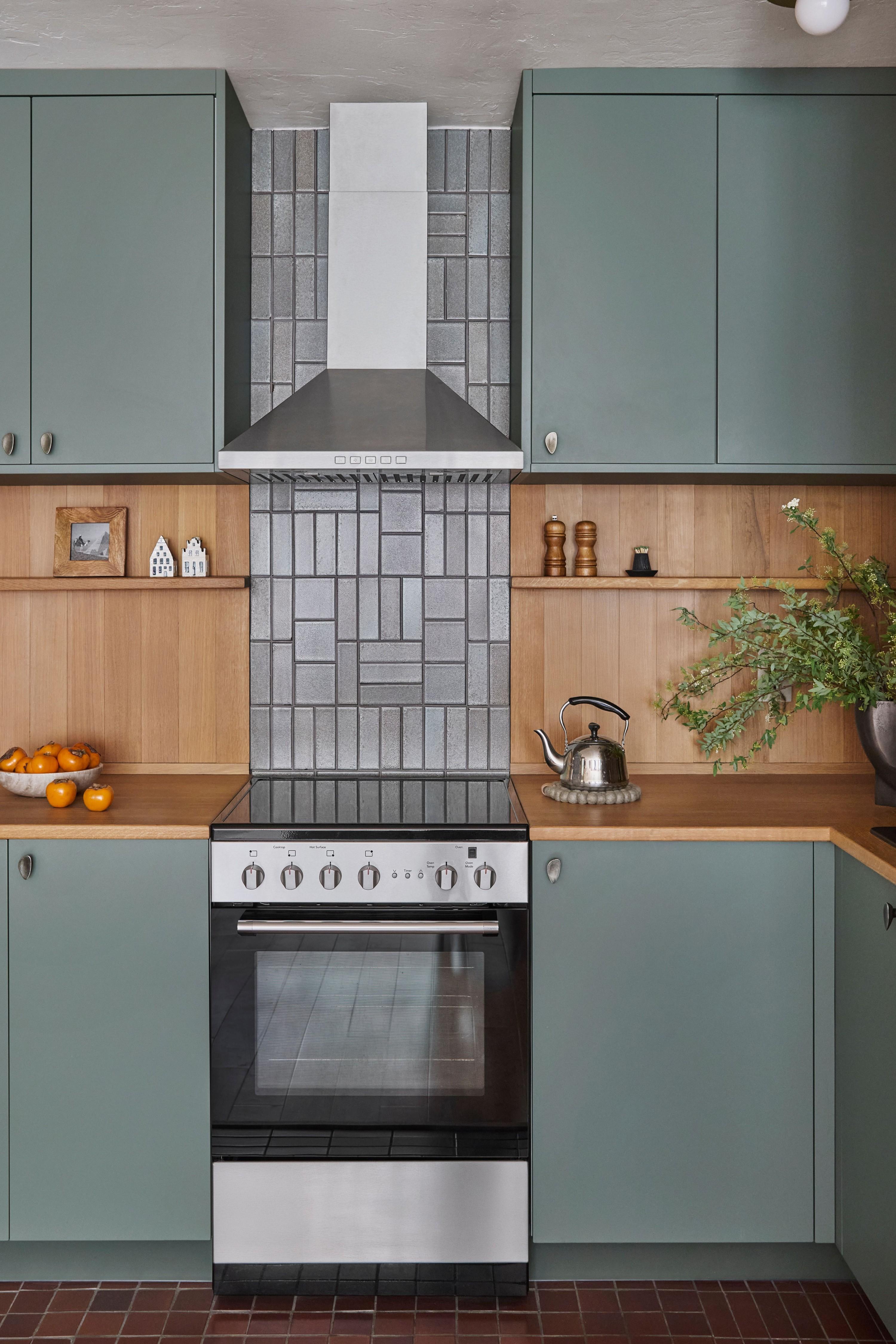 Kitchen with sage green cabinets, white oak surround, and patterned tile backsplash, designed by Studio VAE.