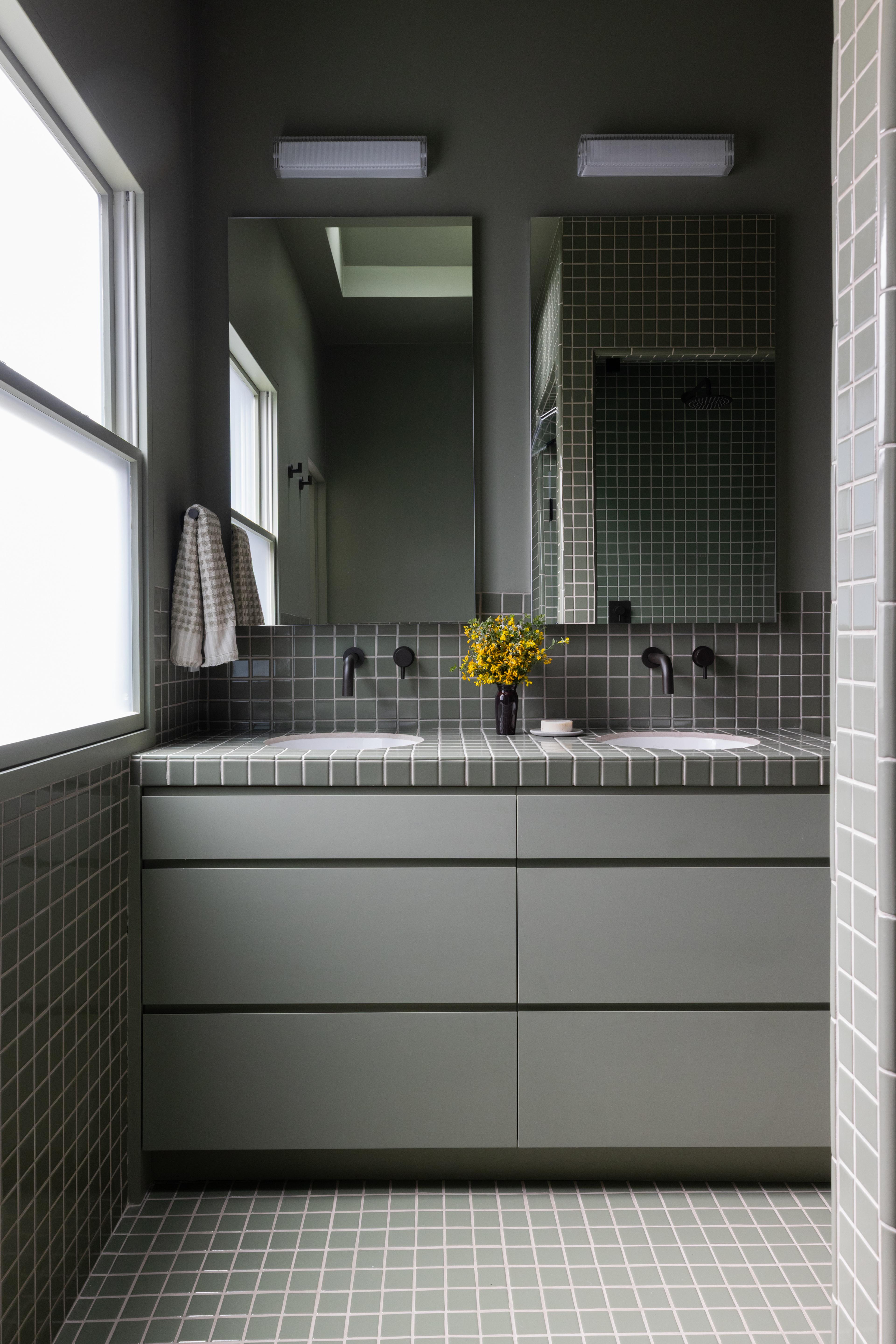 Primary bathroom with double sink vanity, green tile counter and floor, and matte black wall faucets designed by Studio VAE, San Francisco interior designer.