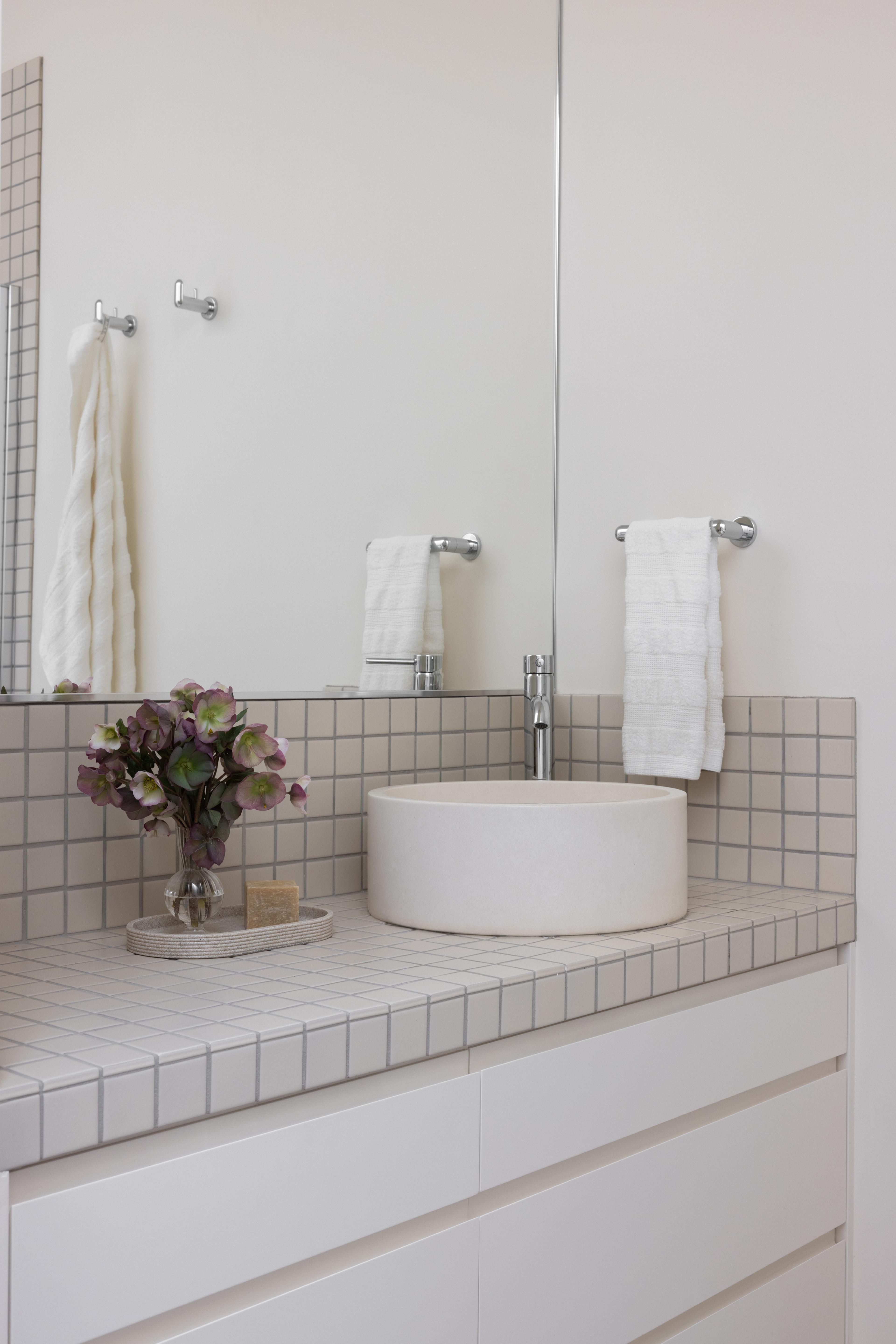Bathroom detail with tiled countertop vanity, paired glass sconce, and original door hardware, designed by Studio VAE, San Francisco interior designer.
