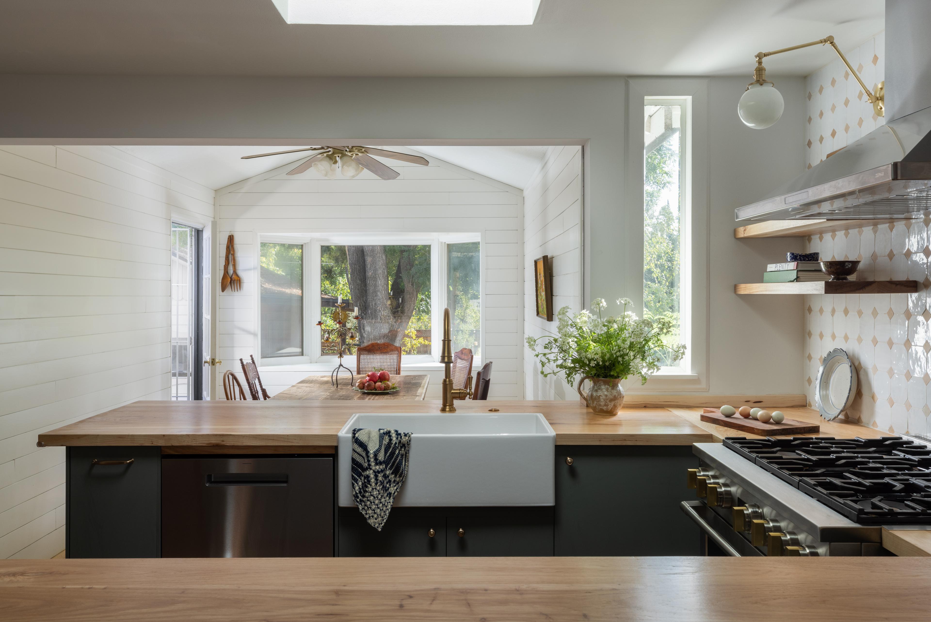 Open kitchen with skylight, farmhouse sink, hickory countertops, and view through to dining room designed by Studio VAE.
