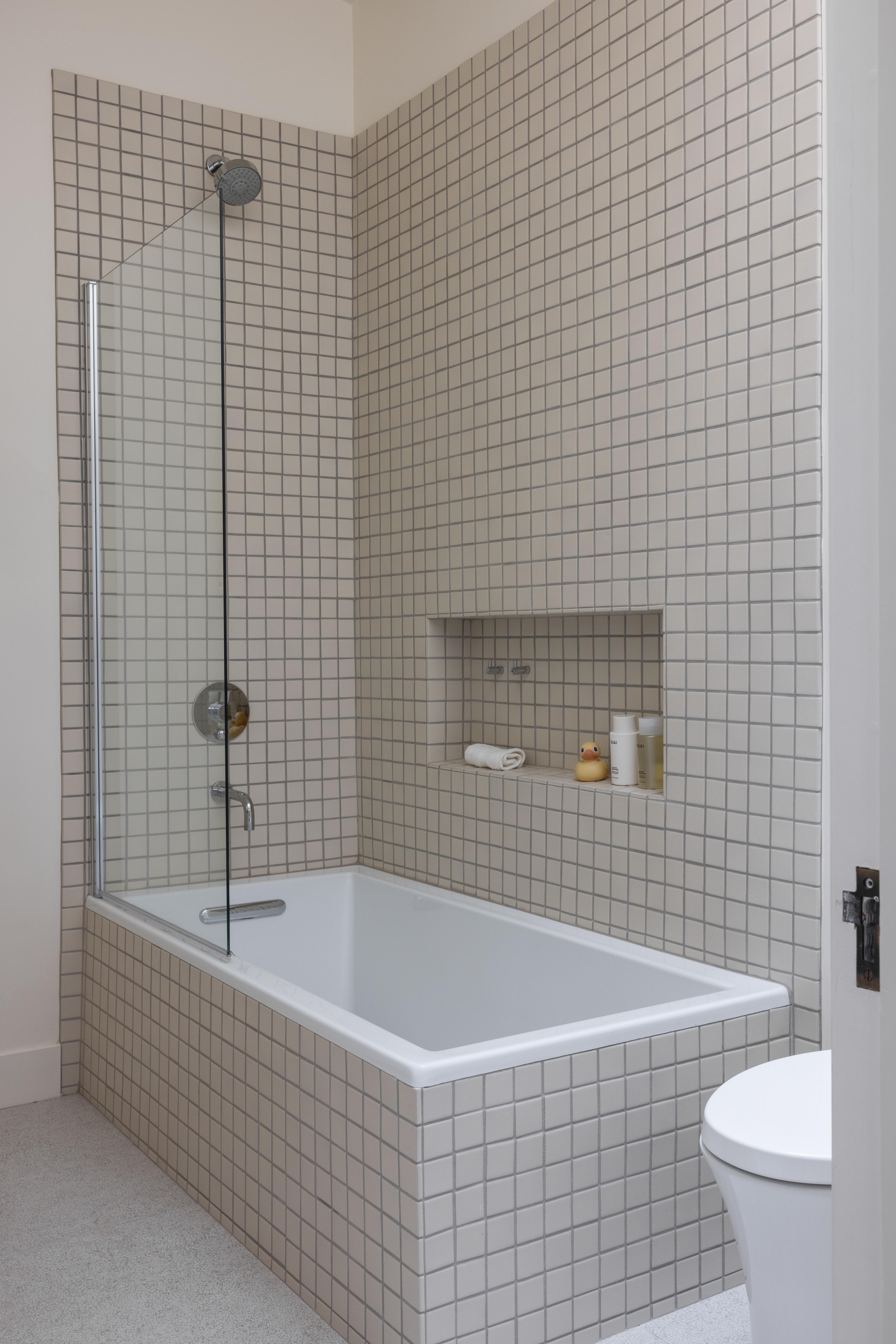 Bathtub-shower combo with grid mosaic tile and recessed niche, designed by Studio VAE, San Francisco interior designer.