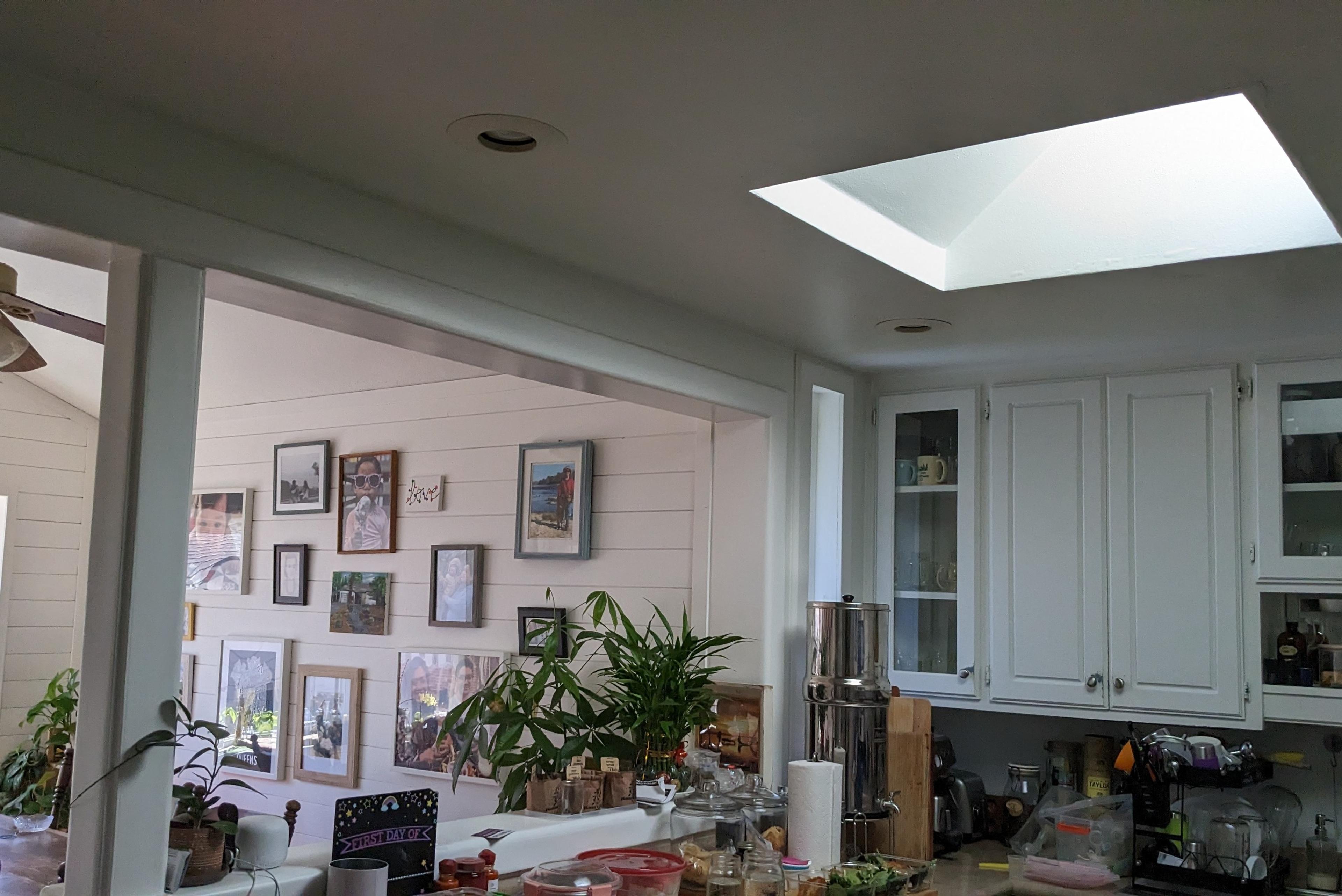 Carmichael kitchen before the renovation, with white cabinets under the skylight and the opening to the sunroom beyond